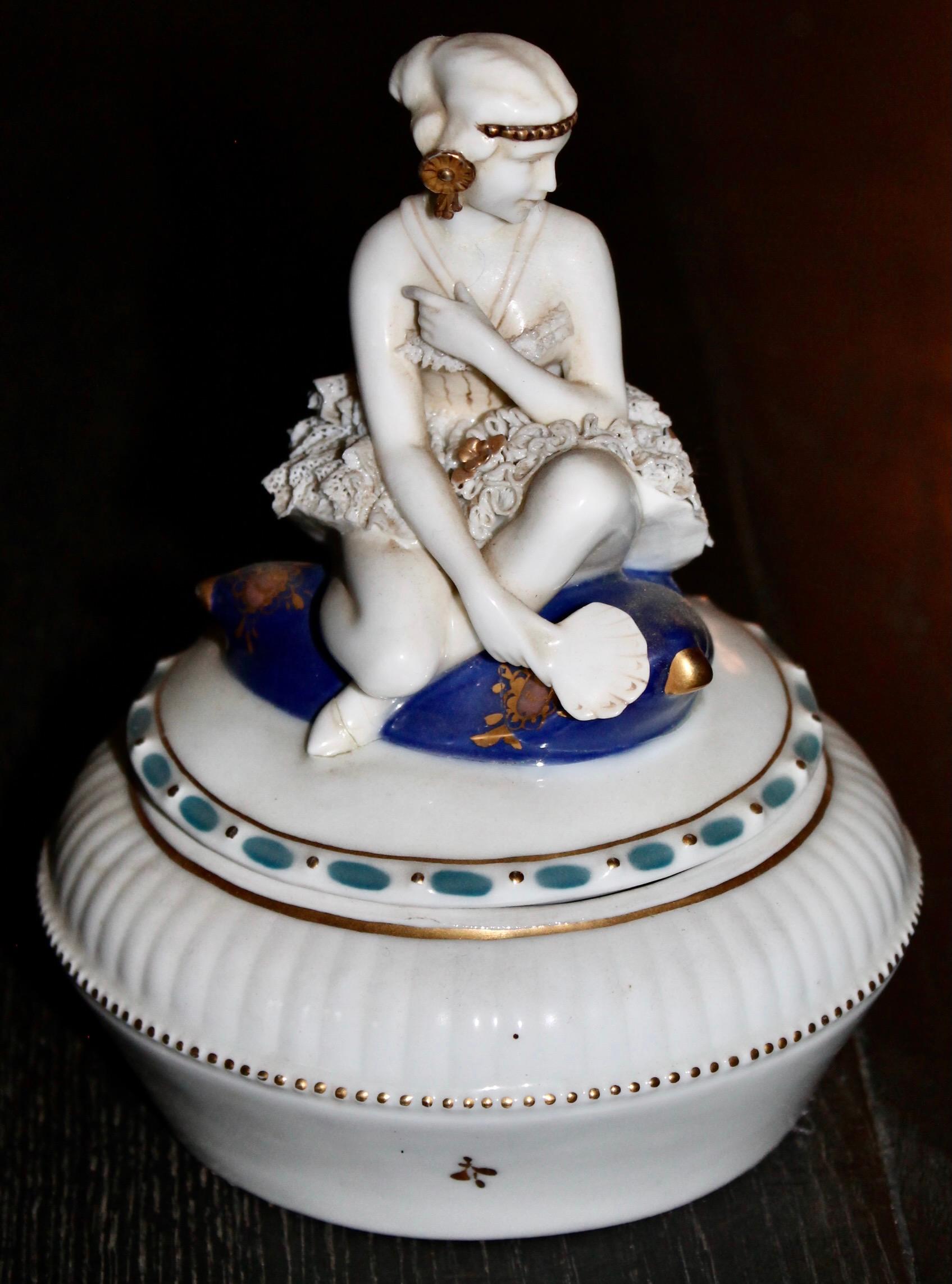 A low circular porcelain container with a lid depicting a young stylish dancer
in costume holding a fan.  Highest quality sculpting and execution. Hand painted detailing in gold and blue. From 1895-1927 Porzelianfabrik E & A Muller created rare