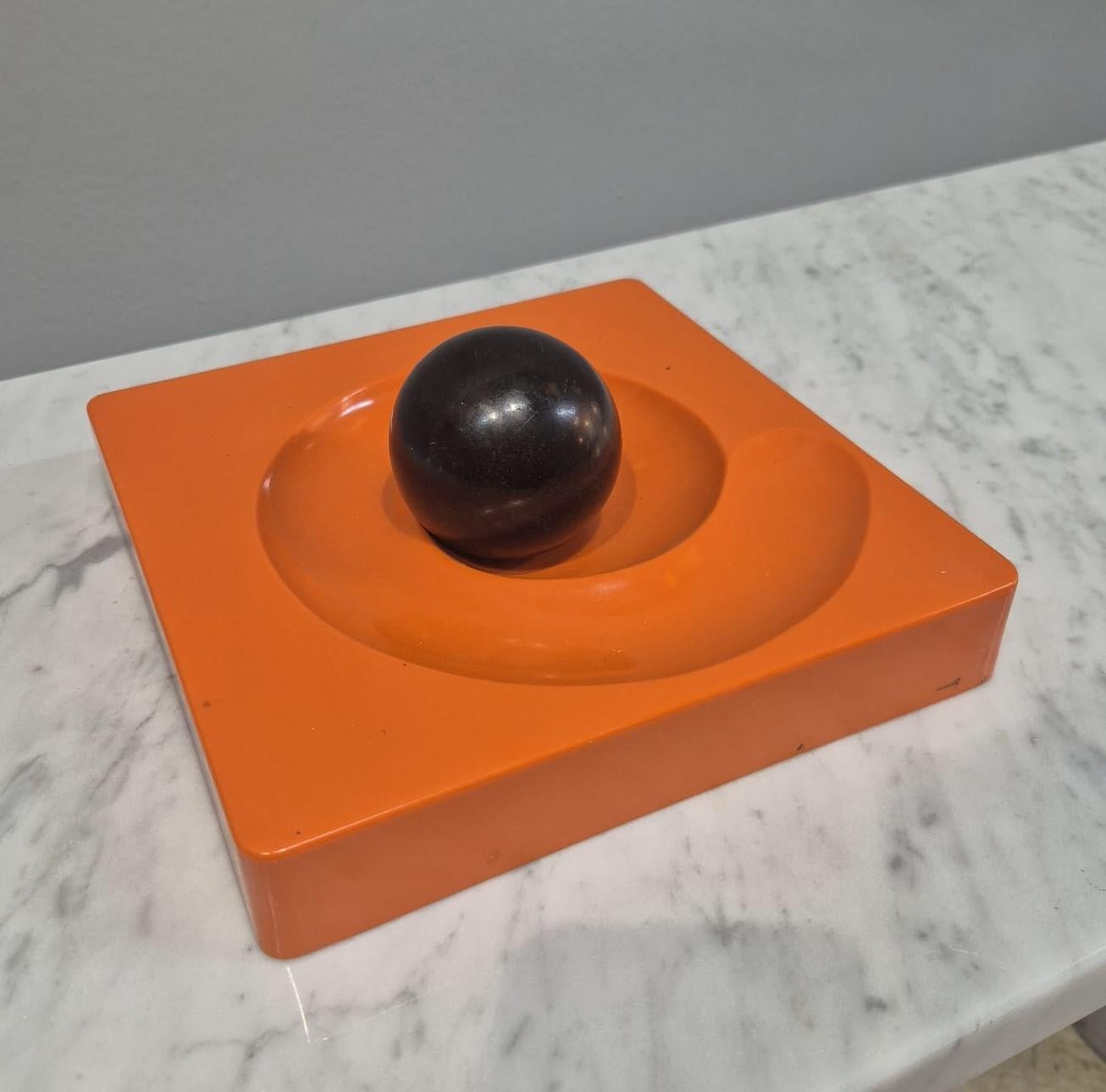 Spiros ashtray in orange plastic by Peduzzi Riva for Artemide, 1960s.
Spiros ashtray with square black plastic base on which is a spiral and in the center is the original black Ball.
The ball runs in the spiral and puts out the cigarette.
Designed