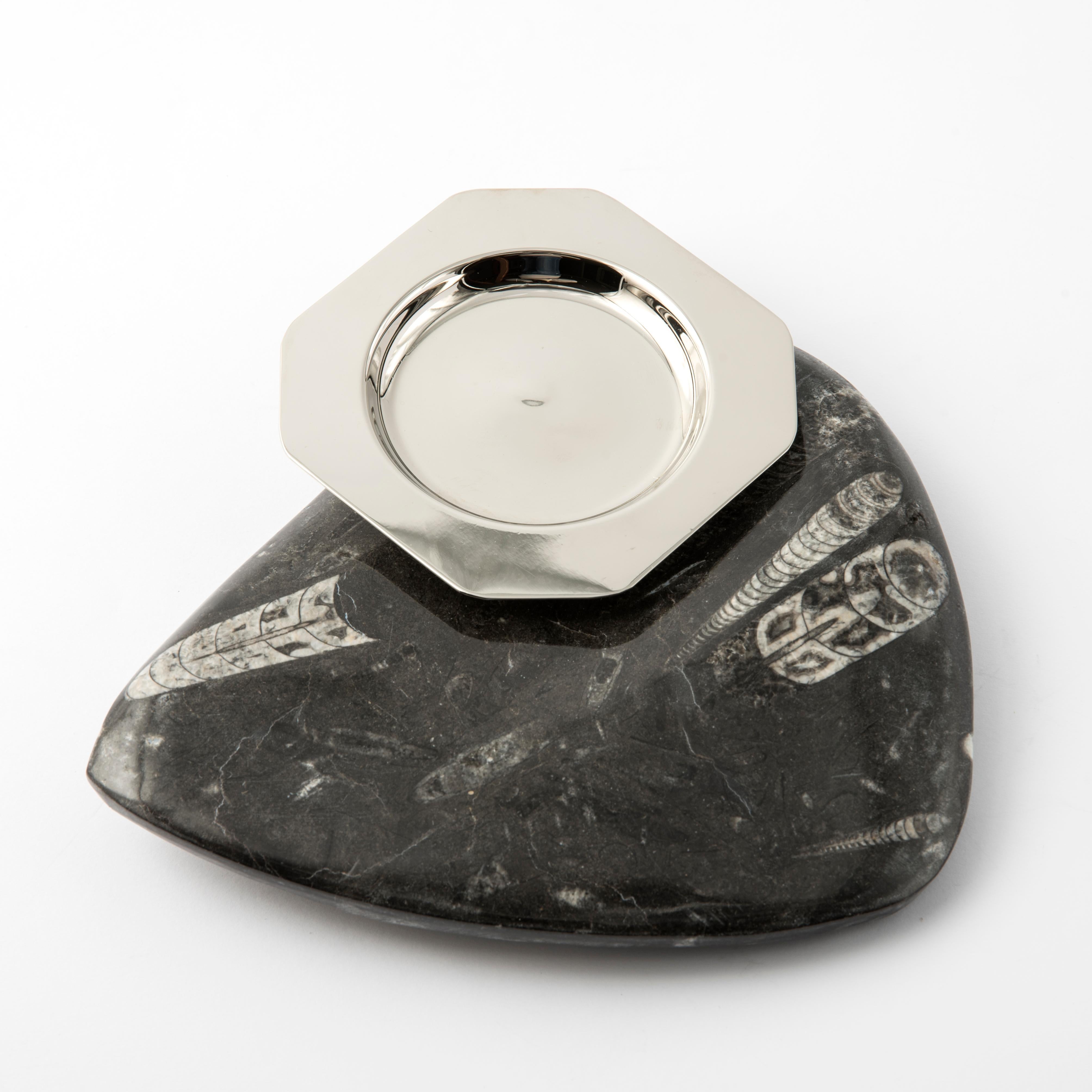 Straordinario oggetto decorativo, questo posacenere in pietra fossile è un pezzo unico firmato dal designer italiano Nino Basso.
 La base è costituita da un frammento di roccia levigata naturalmente, dalla forma triangolare irregolare con bordi