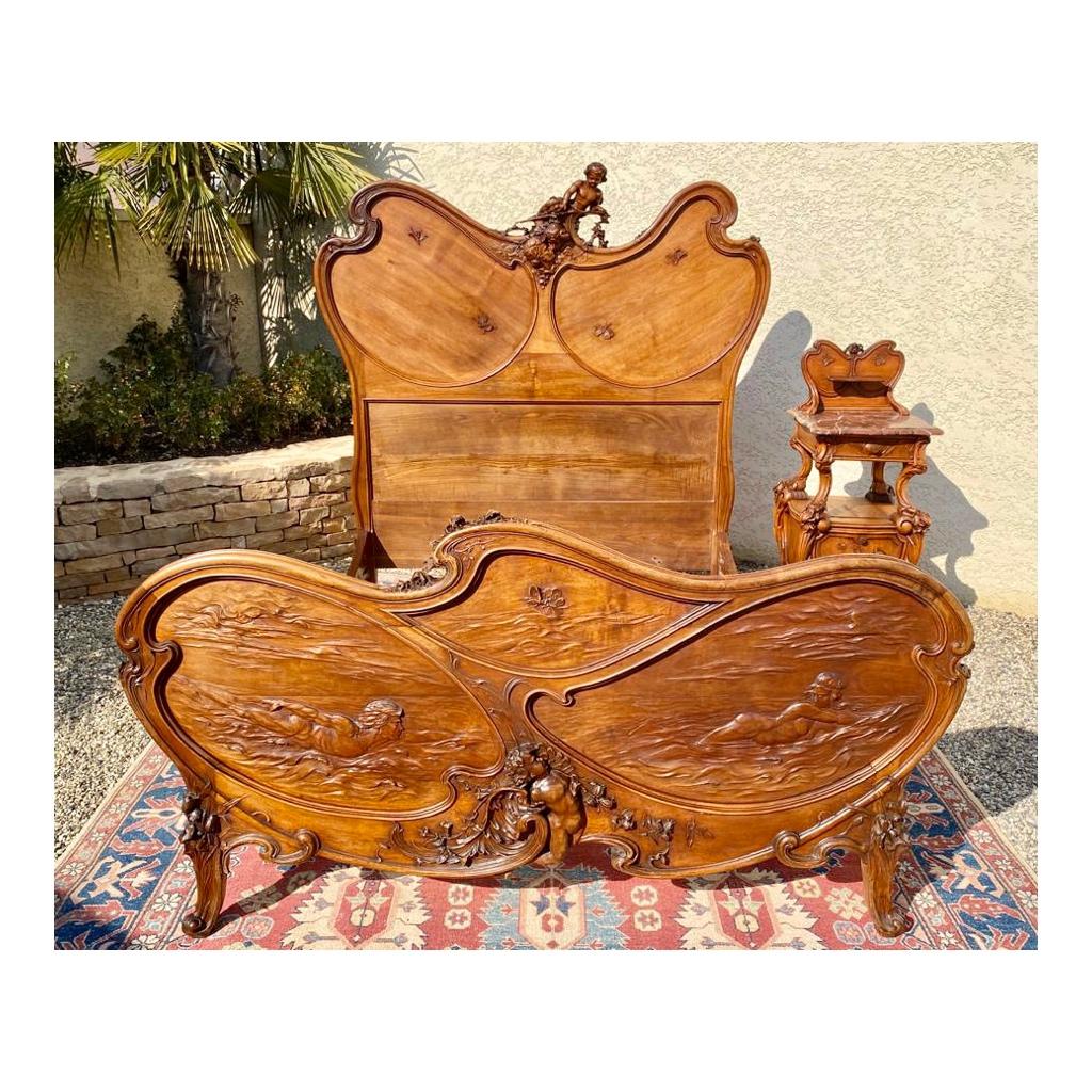 Magnificent Art Nouveau set consisting of a superb bed and its bedside in walnut entirely carved with flowers and insects such as butterflies and dragonflies. The head and the footboard are in the effigy of a mythical couple from Greek mythology,