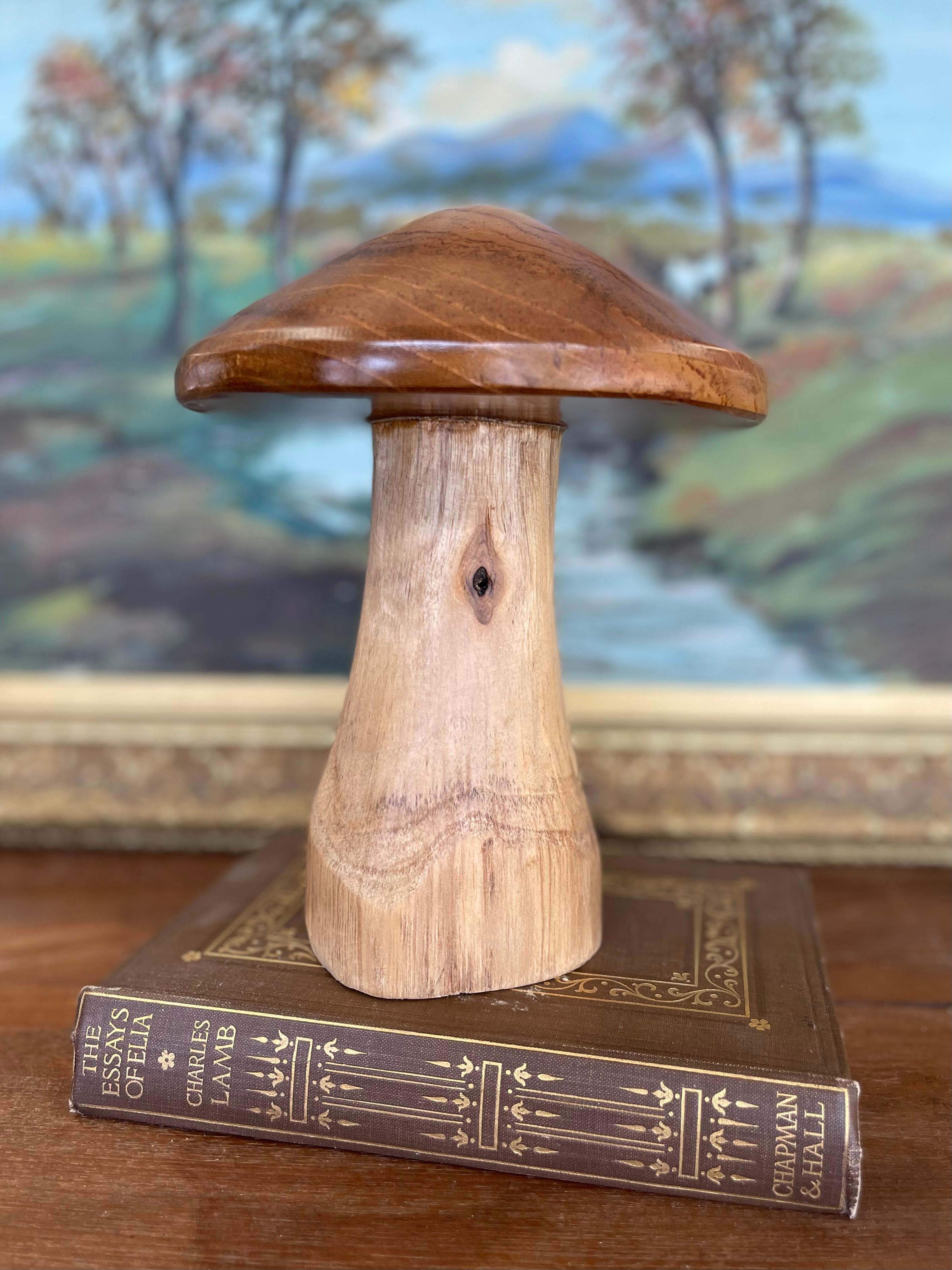 Champignon décoratif fabriqué en studio à partir de bois durs massifs : un chapeau chaud, brun miel, marié à une tige naturelle plus claire. Un travail de tournage habile met en valeur le grain cathédrale fluide du chapeau et le nœud organique de la