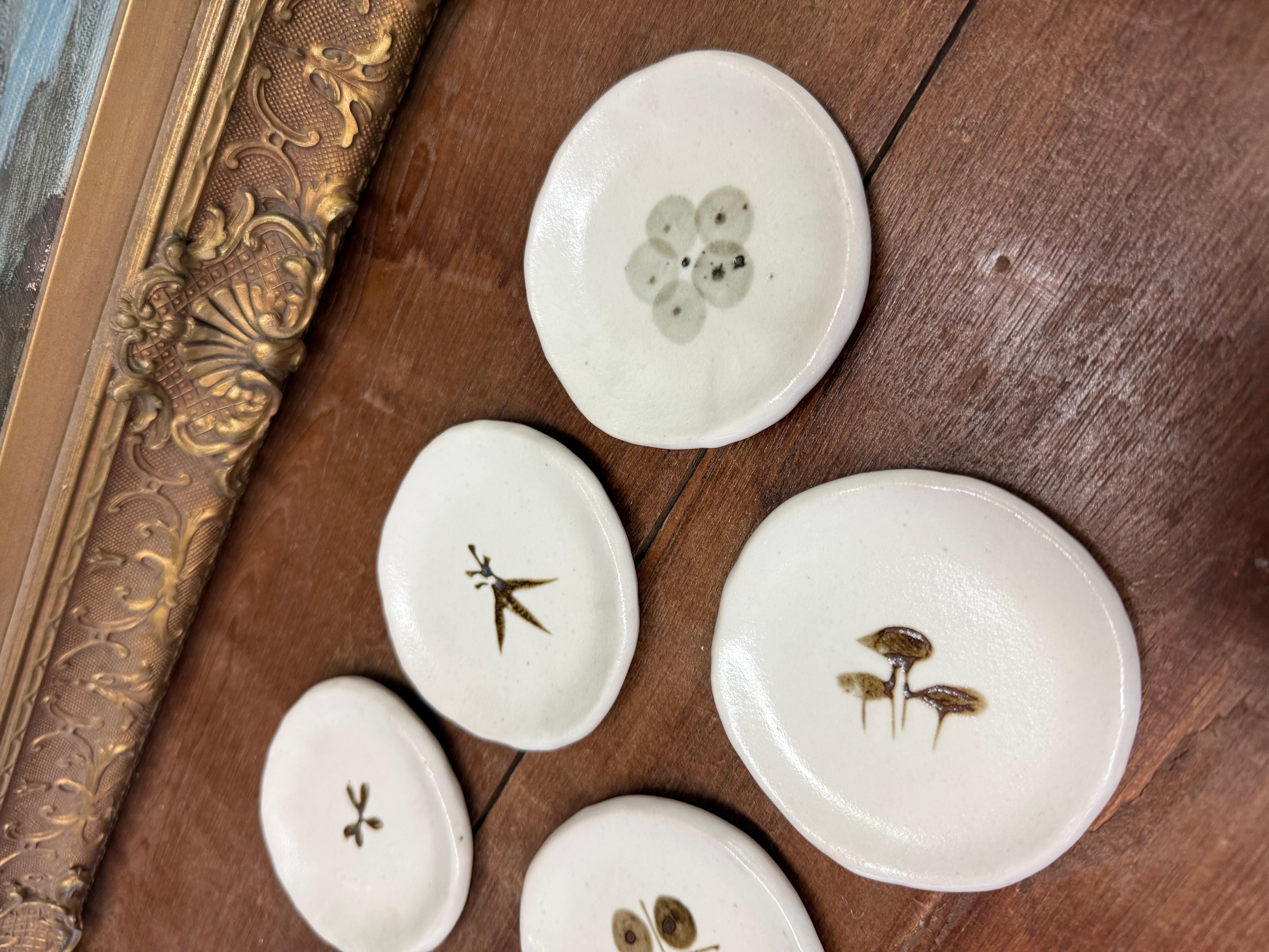 Ajoutez une touche de charme organique à votre espace avec ces bibelots en céramique fabriqués à la main ! Chaque plat est individuellement formé et émaillé dans un blanc doux et naturel, avec de délicates empreintes botaniques dans des tons