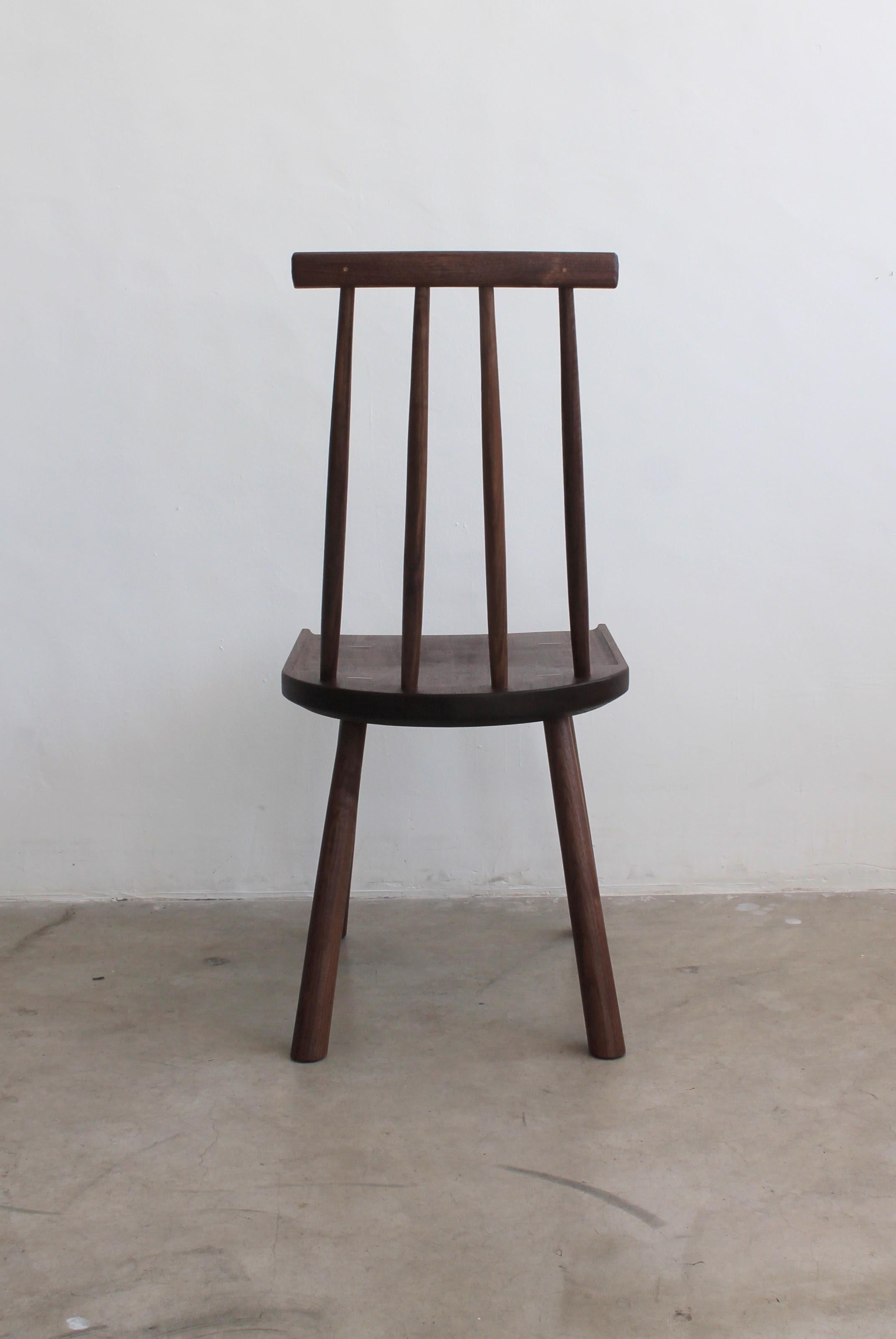 Ispirata alla semplice eleganza del design Shakers, la sedia da pranzo Post Design distilla le caratteristiche della seduta con schienale a fuso nella sua forma più elementare.  Il sedile in noce sagomato a mano funge da ancoraggio per tutti gli