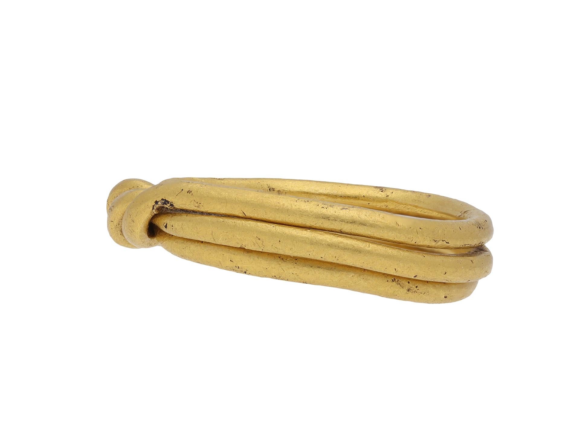 Postmittelalterlicher Goldpuzzle-Ring. Ein Goldpuzzle-Ring, bestehend aus drei miteinander verbundenen Reifenteilen mit einer Drehung an der Spitze. Die drei Teile können zusammengedreht werden, um ein gewundenes Metalldesign zu bilden. Geprüftes