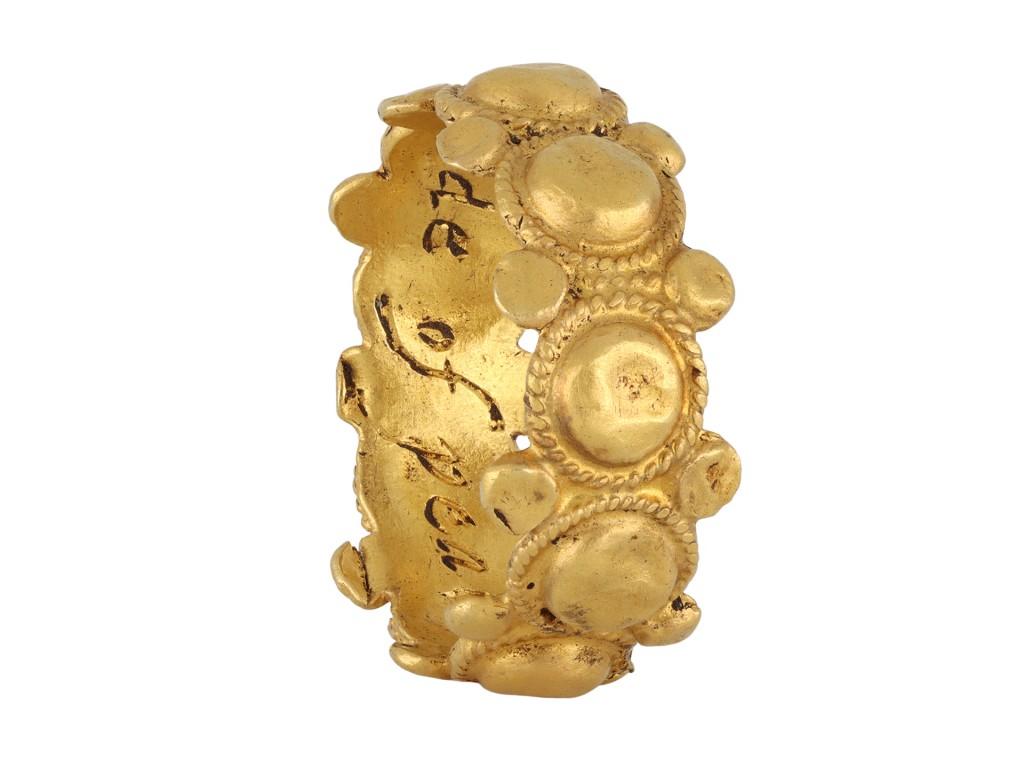 Post-Medieval posy ring 'loue is the bonde of peace'. An ornately crafted gold posy ring featuring nine hollow domed half-spheres, each encircled by twisted wirework, and bordered by further hollow pellets to top and bottom, engraved to interior