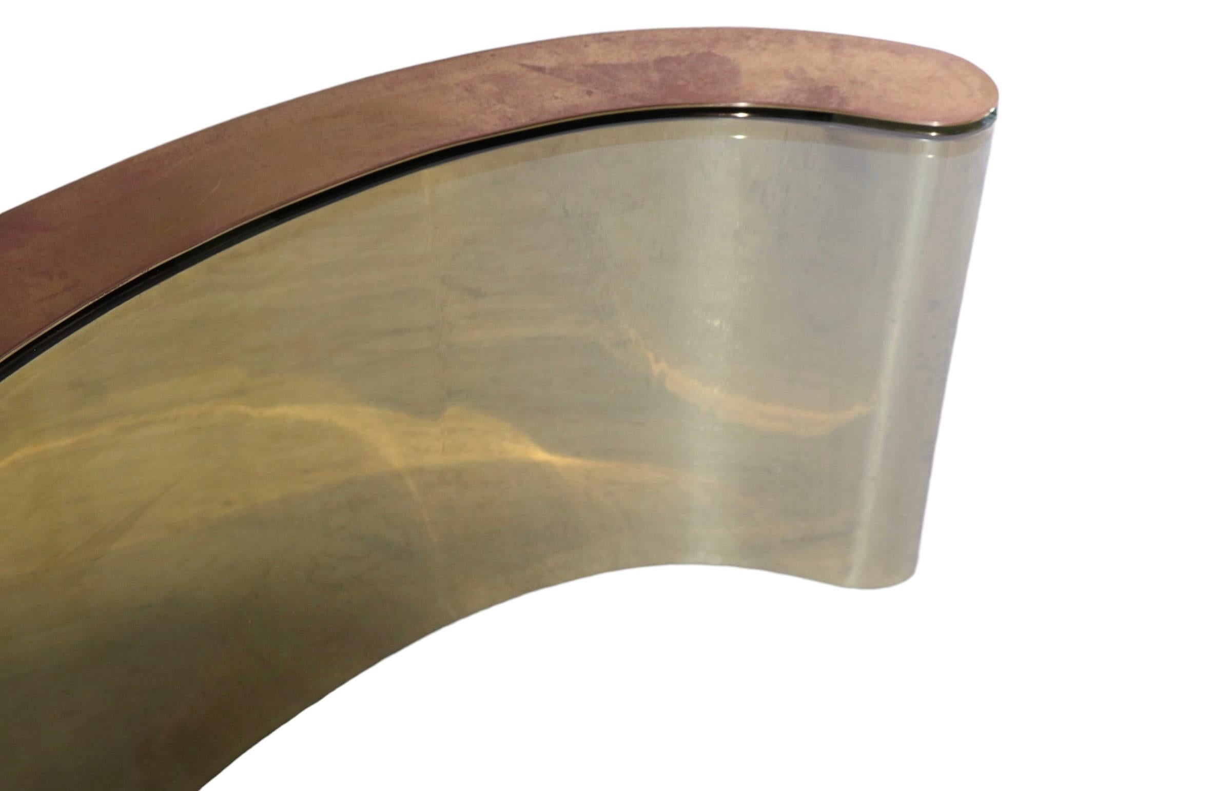 Top quality brass and glass coffee table, having opposing curved brass bases which support the thick (  .75 in. ) oval plate glass top. Executed in the style of Springer, Pace, and other top quality makers, this example is unsigned. 
 The brass