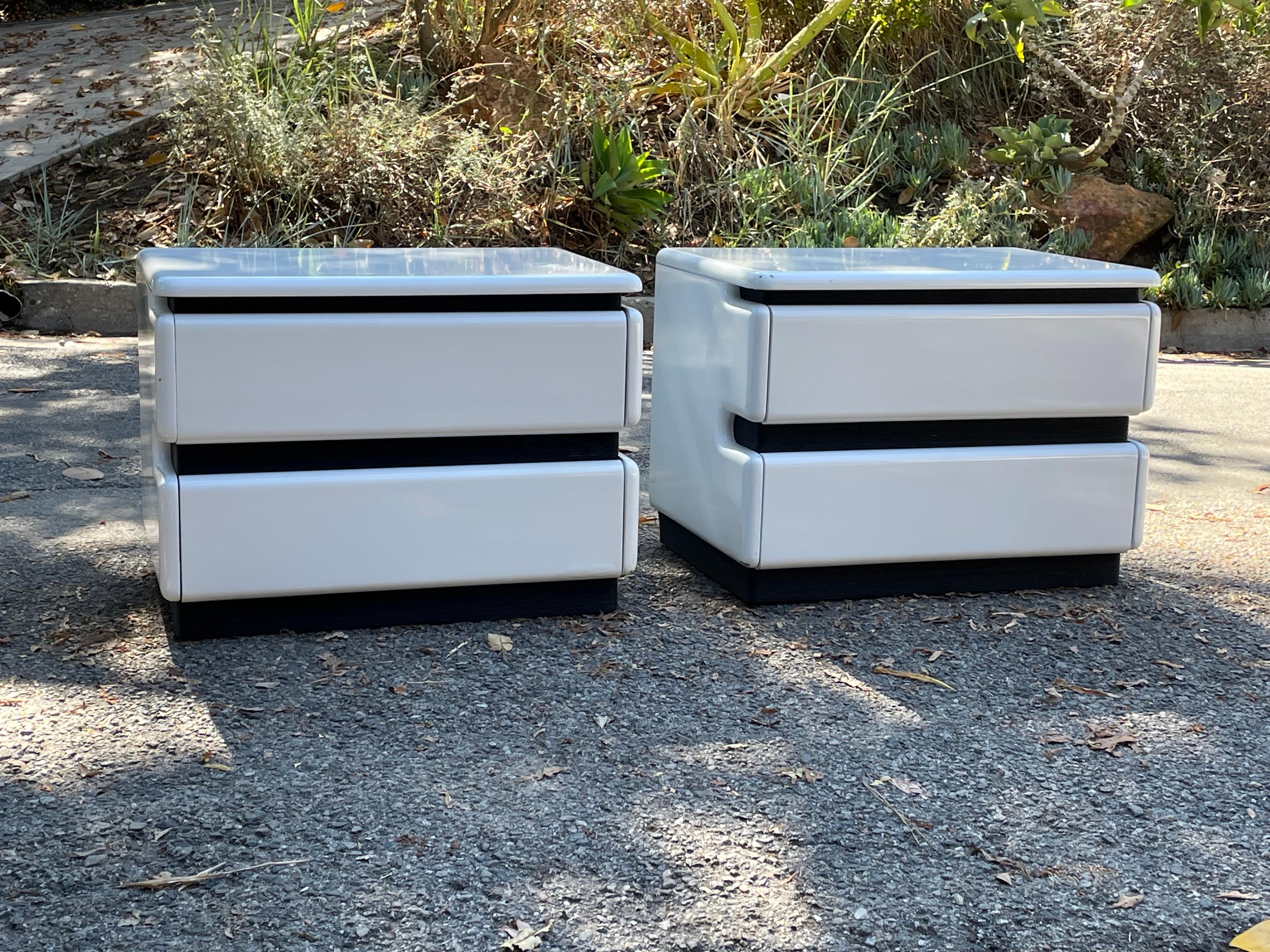 Vintage Post Modern two drawer white gloss lacquer nightstands, circa 1980 by Roger Rougier.

Features a timeless space age design with white lacquer, black rubber accents and two generous drawers with hidden pulls.

We're currently pairing these