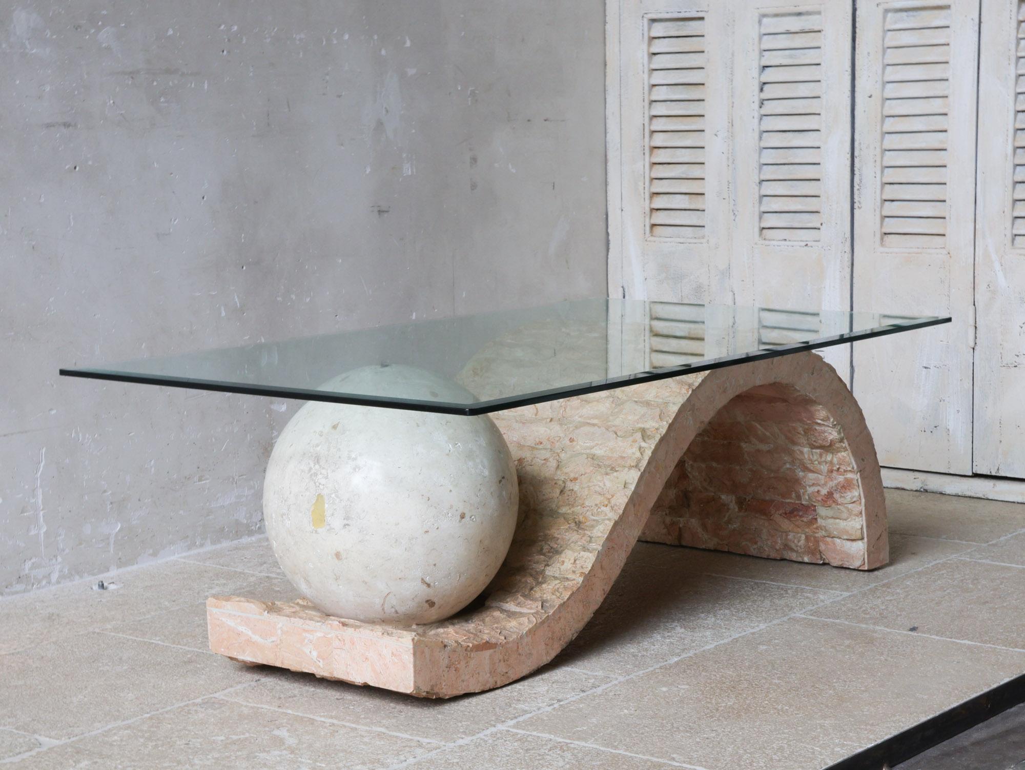 This vintage coffee or side table from Magnussen Ponte, from the 1980s, has a unique postmodern design, with geometric shapes and coarse structure, with the smooth sphere on top that supports the glass top.

The table is made of Mactan stone, also