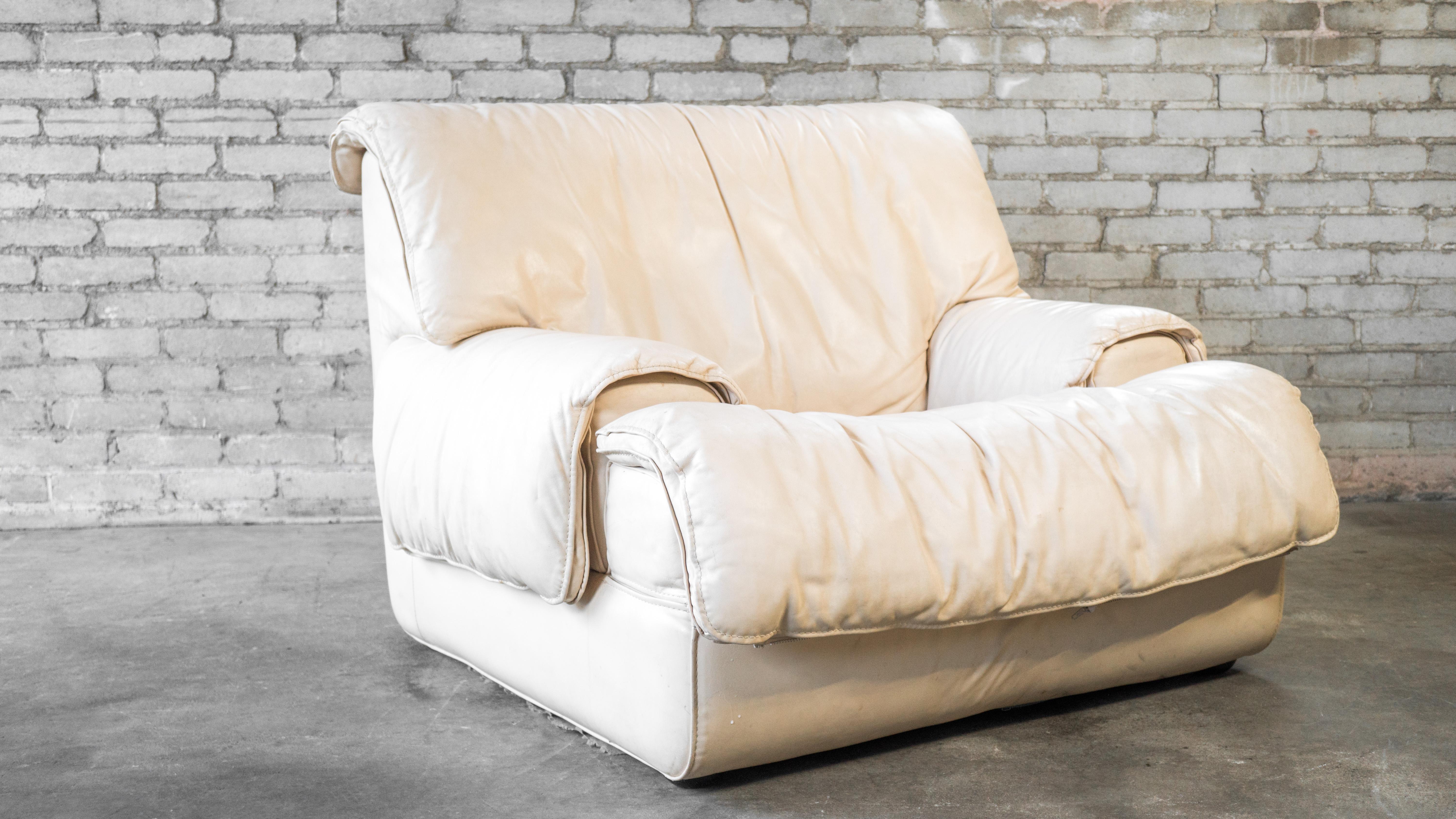 Roche Bobois Sessel aus cremefarbenem Leder, ca. 1980er Jahre. Niedrige Bauweise mit dicker, weicher Polsterung. Lederfalten über den Armen und der Rückenlehne sorgen für eine entspannte Atmosphäre. Die Sitze sind sehr niedrig und fesselnd. Guter