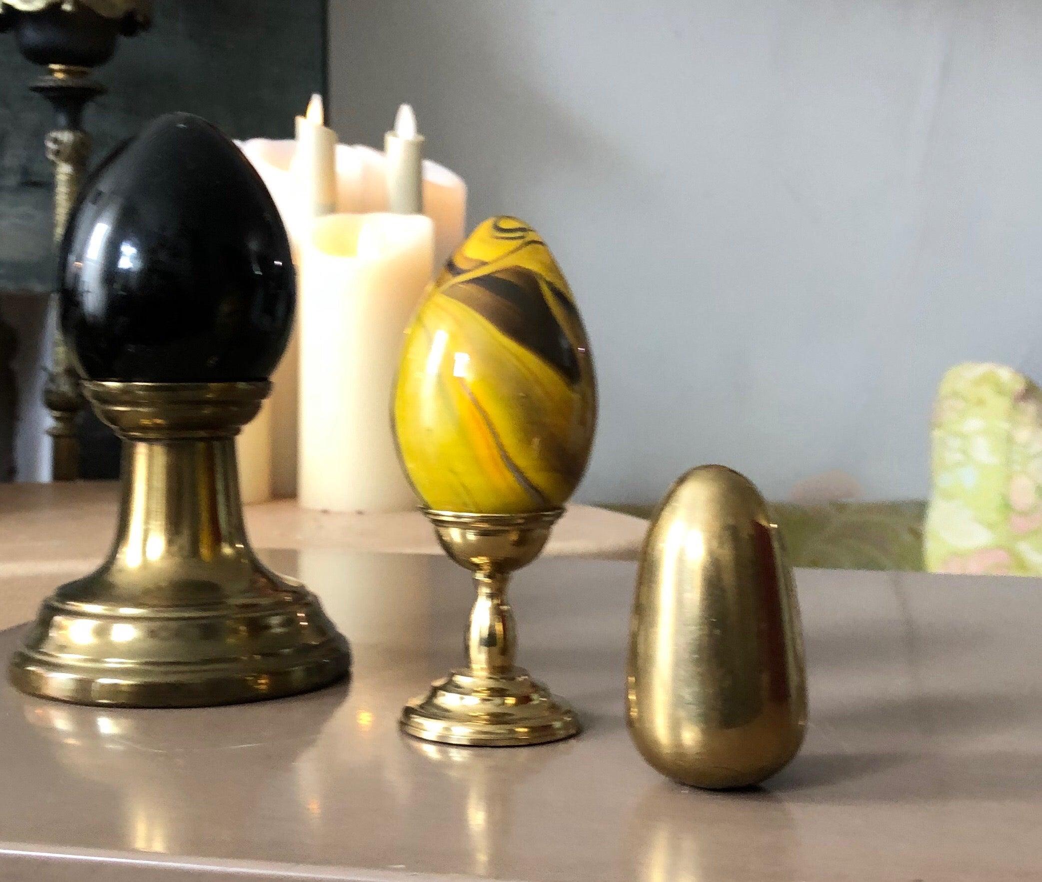 Carefully curated trio of glass and brass eggs with corresponding brass platform bases (2) for display. Set is comprised of 3 eggs and 2 bases.