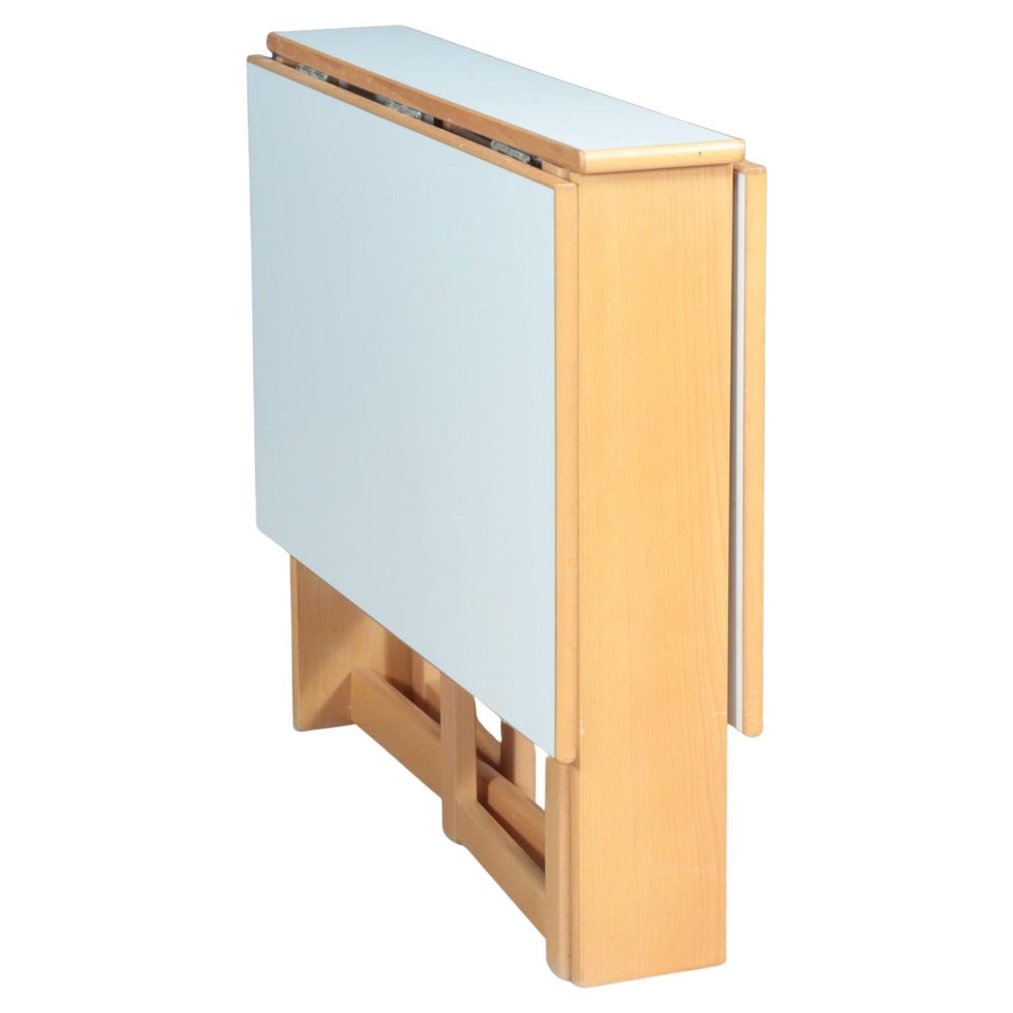 Post modern beech and white laminate drop leaf dining Table. Great small dining table that can fold up and be placed to the side. Table seats 4 chairs/people. In great vintage condition circa 1970. made in Denmark 

Measures 46” x 32” x 30” high