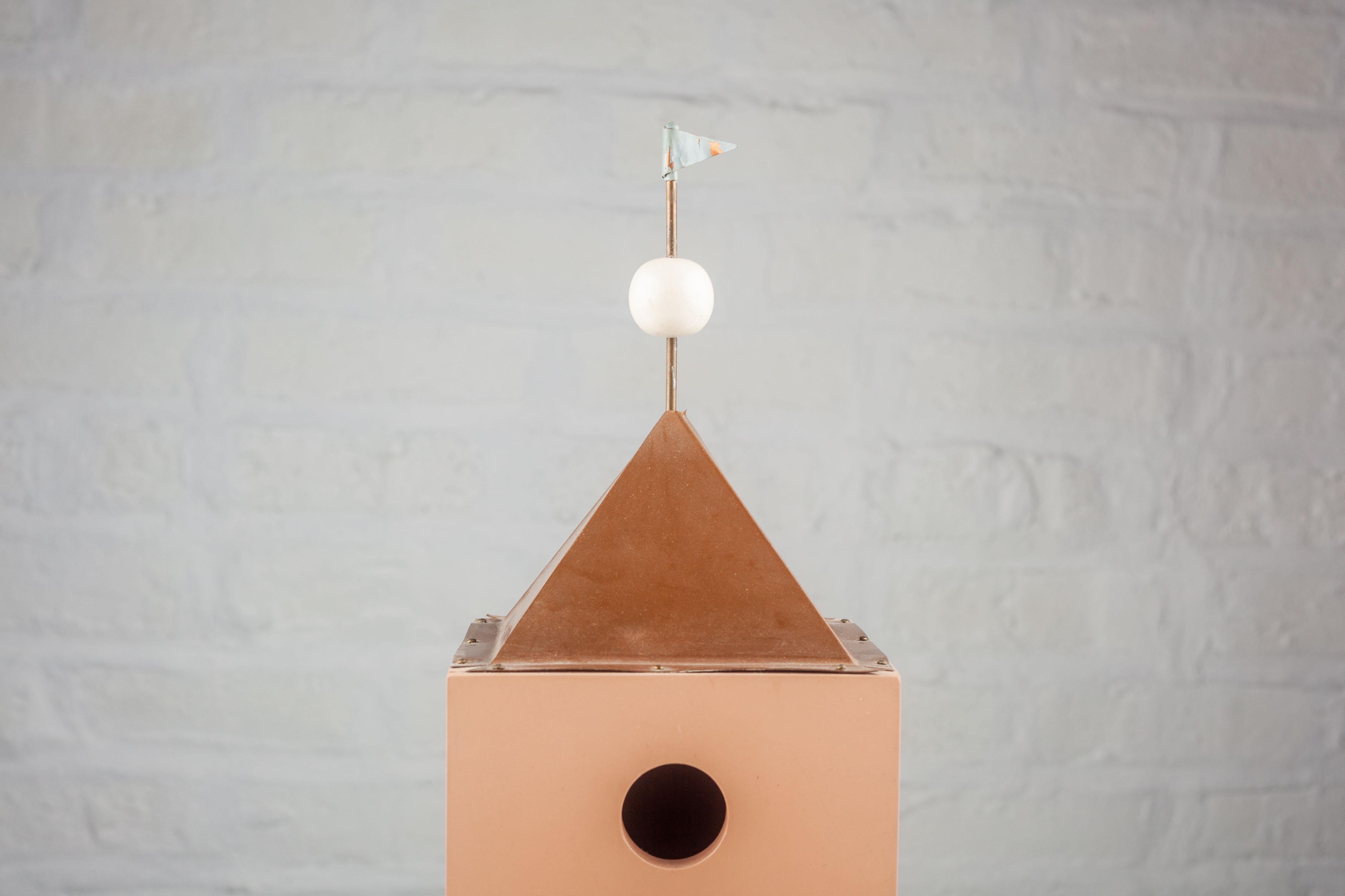 Crafted from painted wood, this architectural birdhouse sports a carefully chosen color palette that is both subtle and elegant, reflective of its time. It boasts a geometric cubic body, with a flat facade and crisp, clean lines that echo the