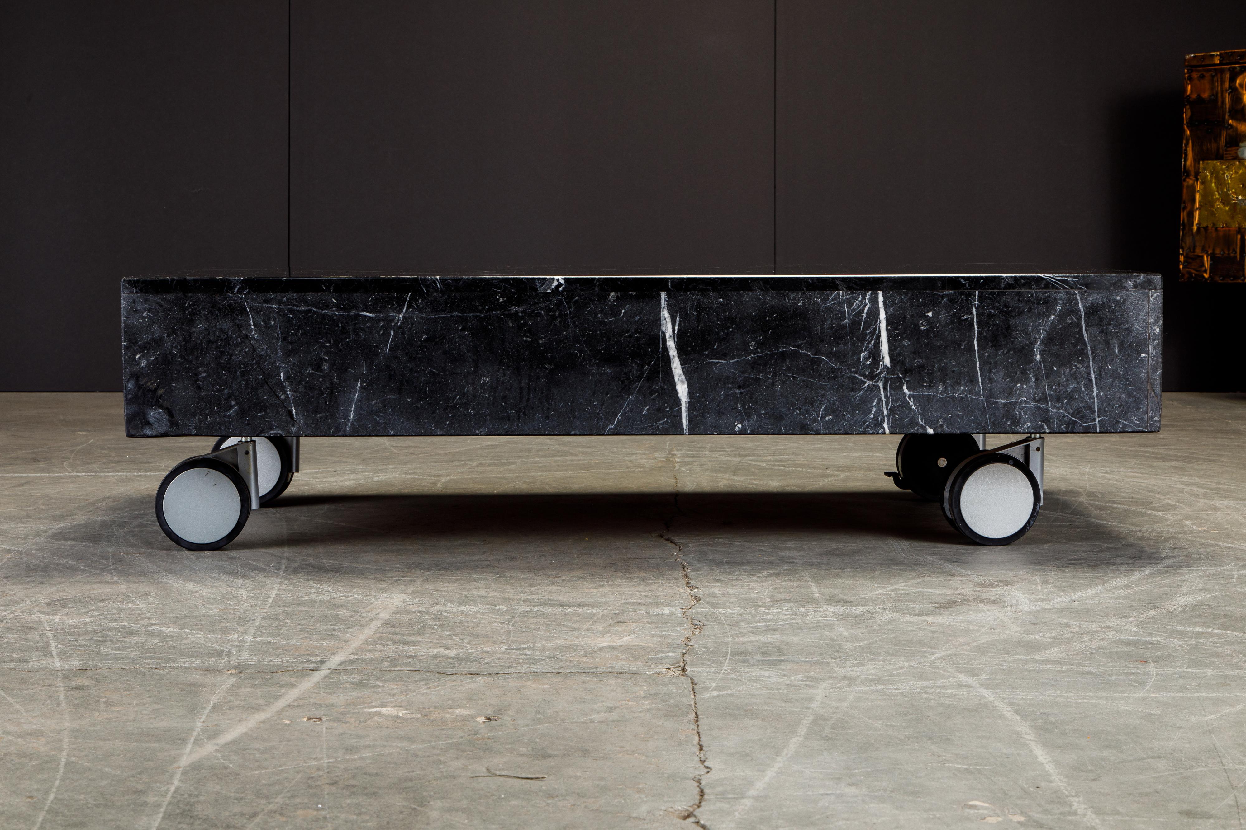 A sizable rectangular Post-Modern black marble coffee table on oversized Italian casters in similar style to Gae Aulenti. 

This Post-Modern cocktail table on casters would work great in a Post-Modern, Mid-Century Modern, Space Age Mod,