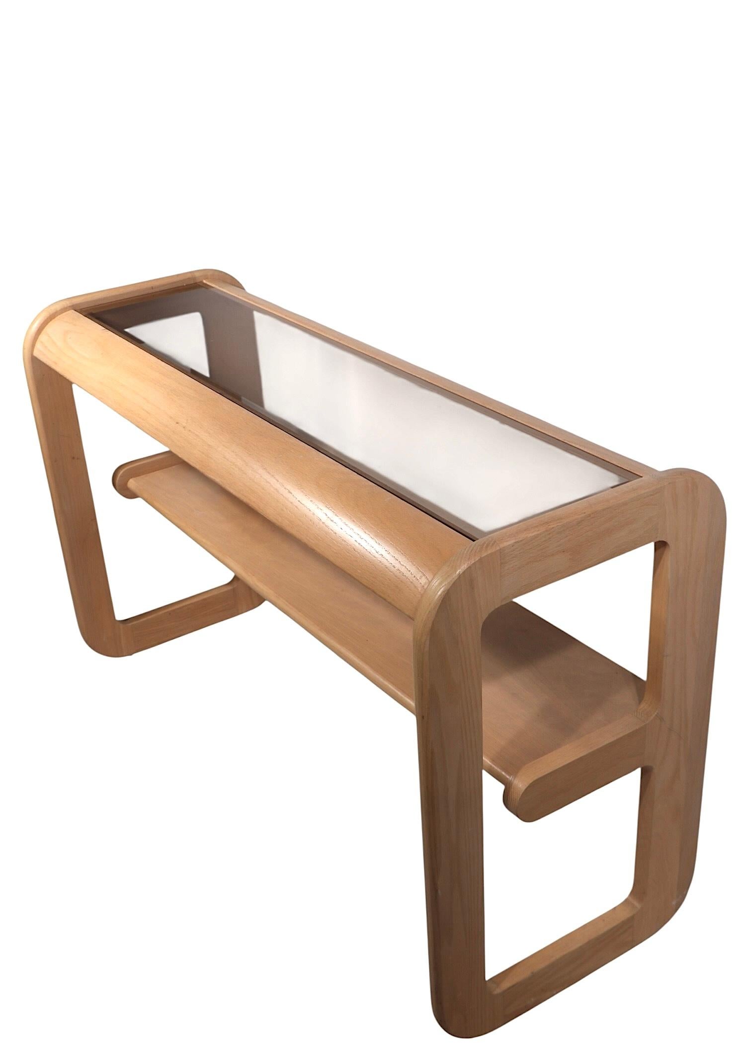 Chic Post Modern console table designed by Lou Hodges, circa 1980's. The table is constructed of solid oak in original bleached finish, with a beveled and tinted glass insert panel top. This example is in very fine, clean, ready top use condition,