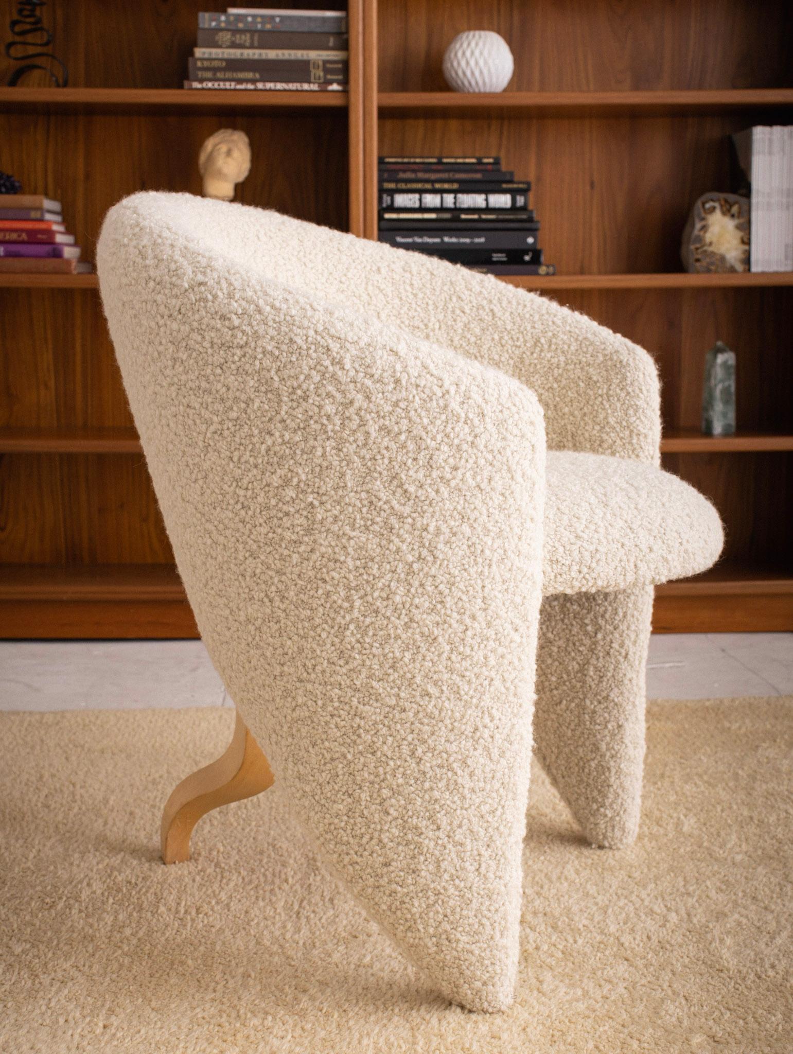Sculptural post modern barrel chair. Back rest wraps around to form 2 front feet giving the chair a floating appearance from certain angles. A squiggle form sculpted wood leg supports the chair from behind. New high pile wool boucle upholstery. 2
