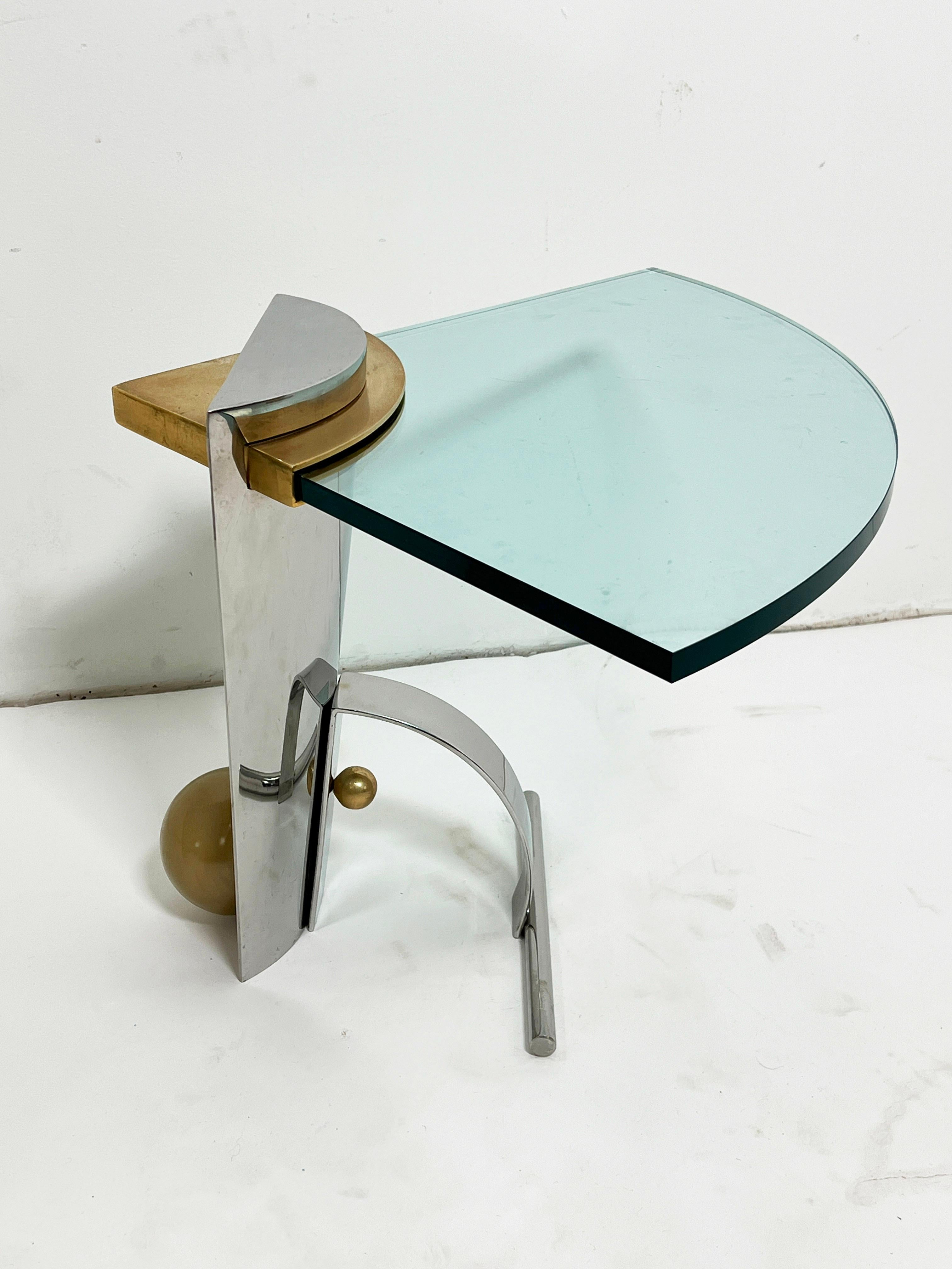 Mixed metal chrome and brass coffee table with a cantilevered glass wedge shaped top, circa 1980s, in the manner of Karl Springer.  The surface height is 18