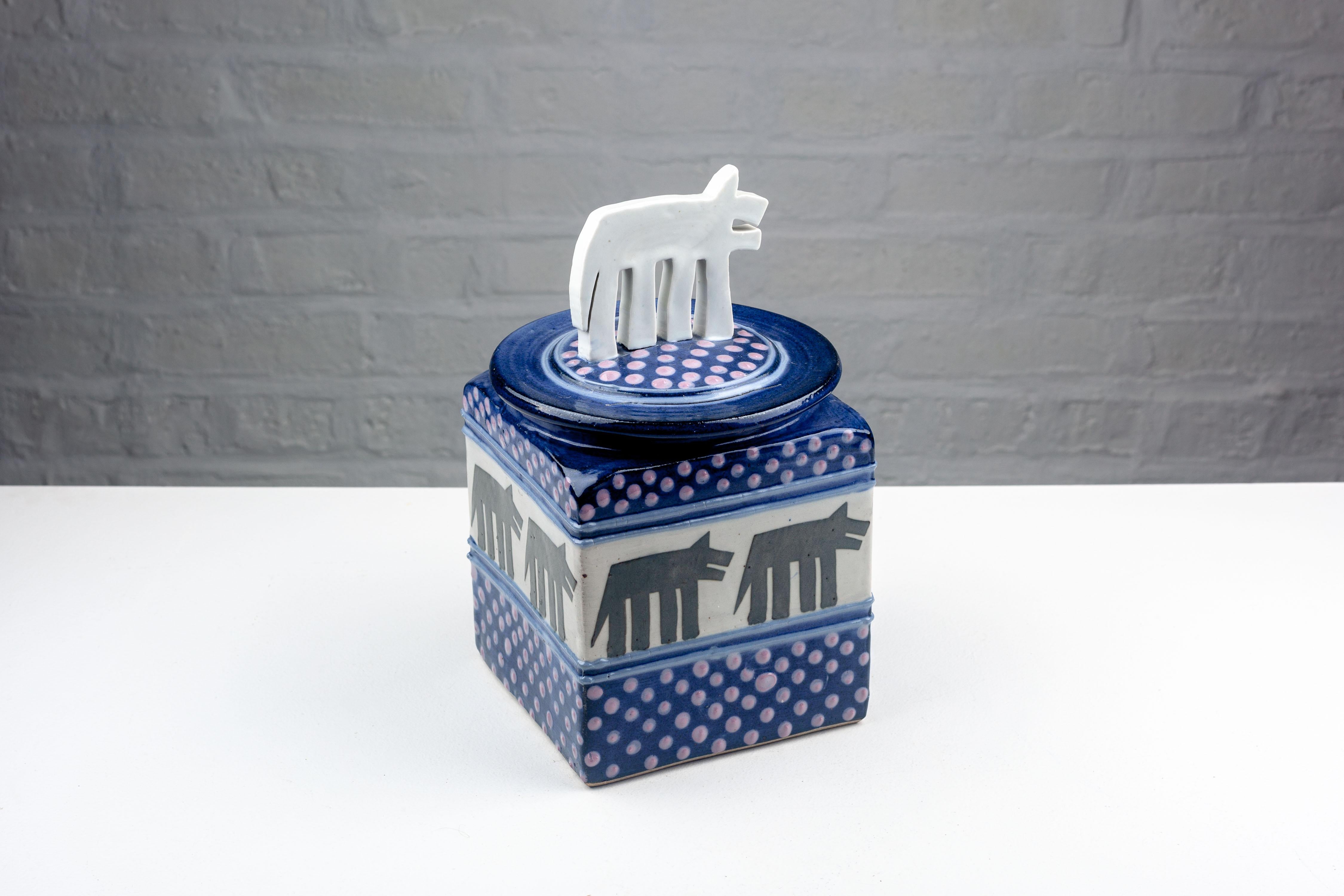 This post-modern ceramic cookie jar, with its distinctive cubic form and playful large dog handle, is a prime example of the unique craftsmanship of Steve and Miky Cunningham from the early 1990s. Handmade at Cunningham Pottery in the Iowa USA, it