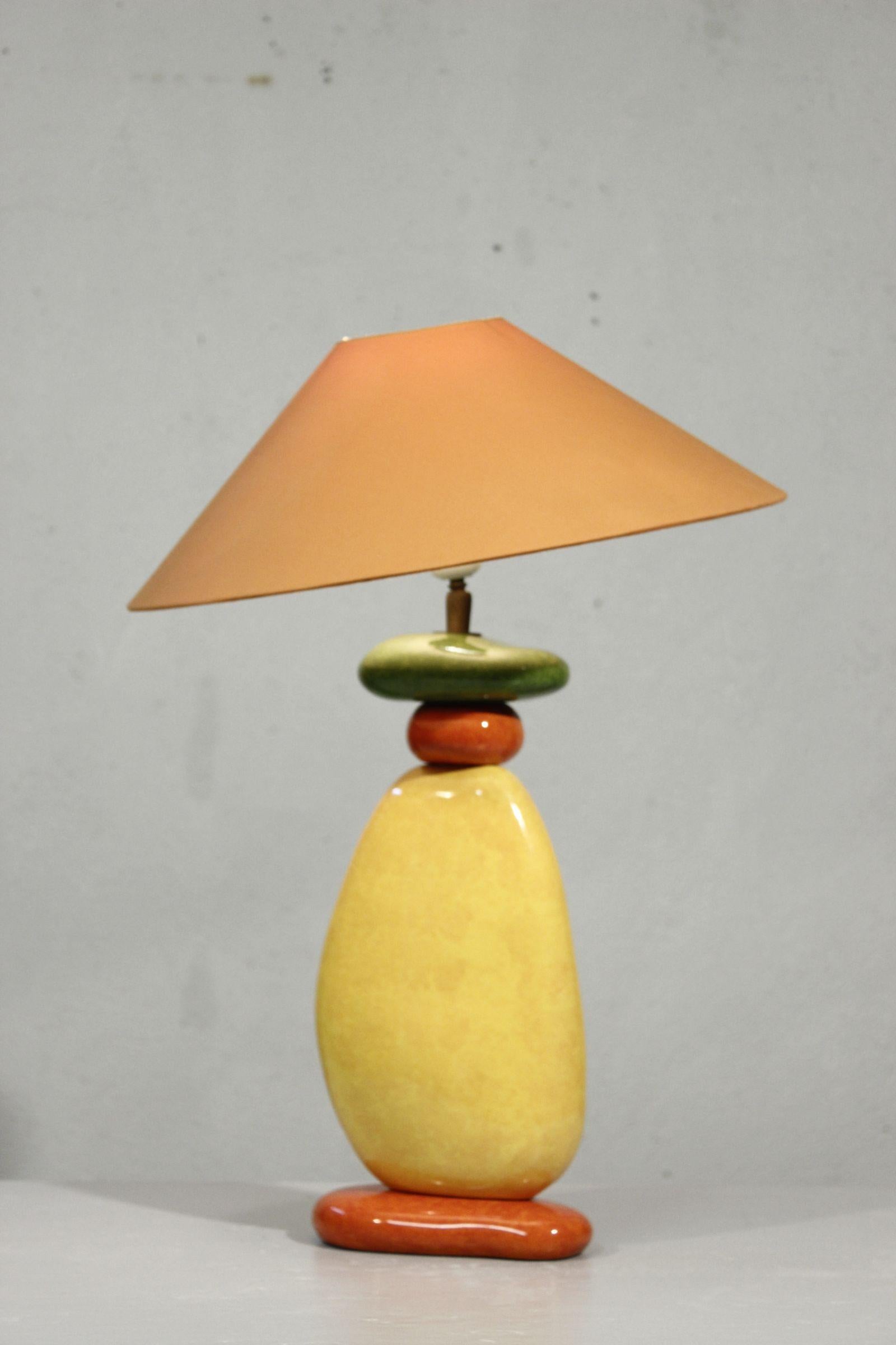 Pebble table lamp designed & produced by François Chatain circa 1990, composed of four ceramic pebbles with alternating orange, yellow, red and green vibrant and shiny enamel.

The base is topped with a brass rod with ball joint which allows the