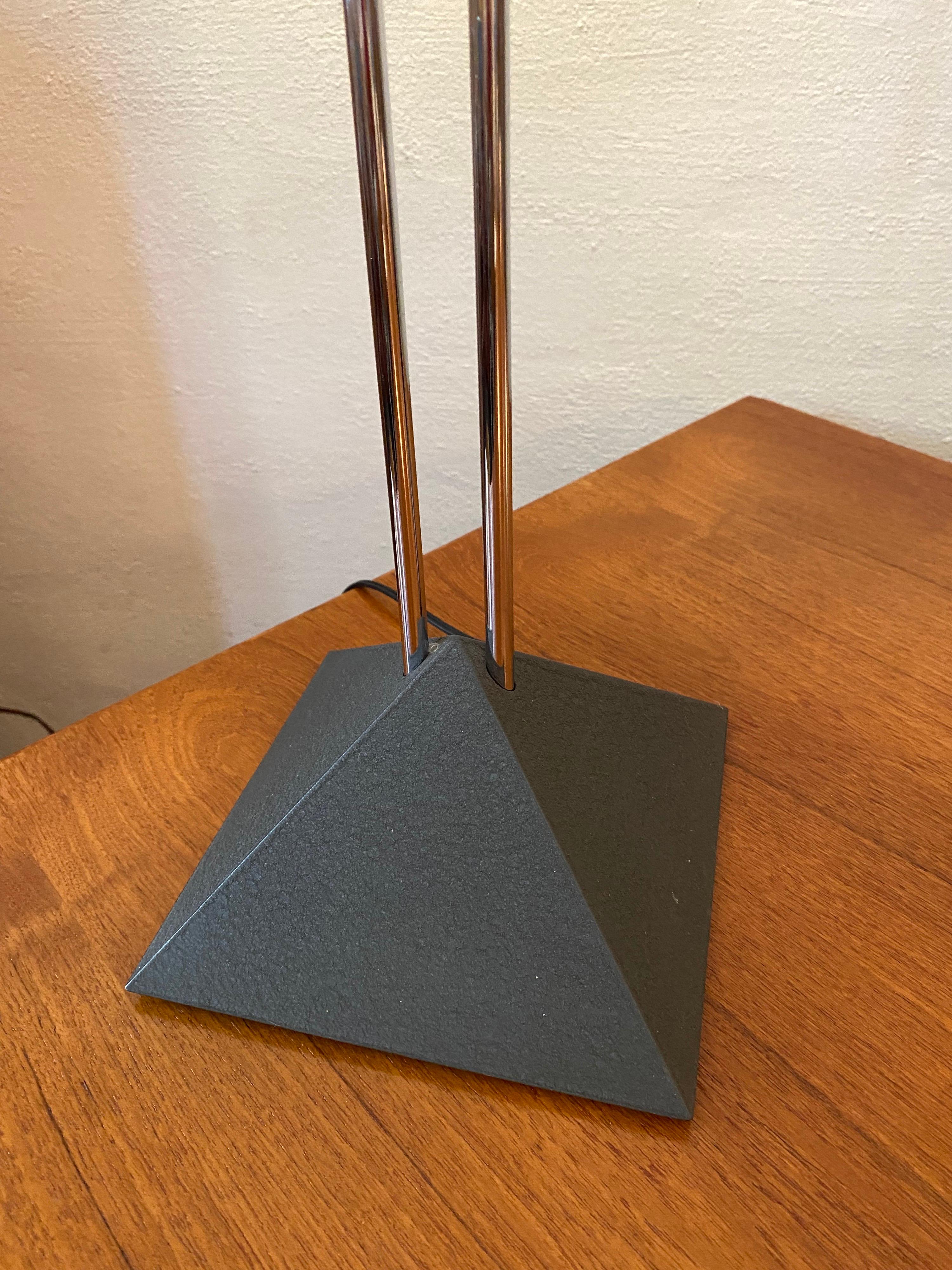 Post modern chrome floor lamp with on line dimmer. 2 simple chrome poles support square turned panels at top where the light source is hidden.