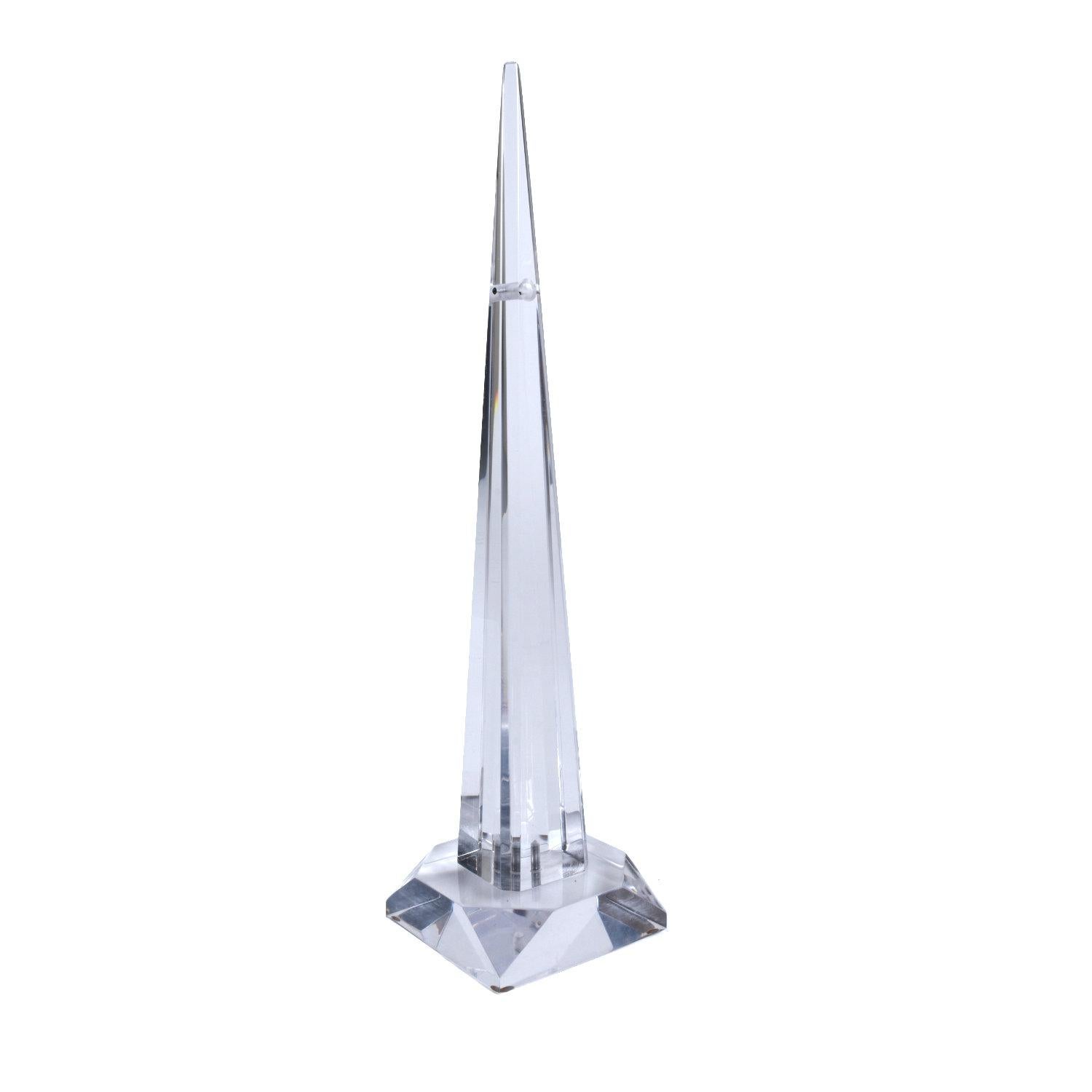 Obelisco postmoderno in lucite acrilica trasparente. Questo monumento da tavolo vintage degli anni '70 presenta un curioso foro nella parte superiore con un'asta di metallo in equilibrio al centro. Il fusto e la base sono sfaccettati, permettendo