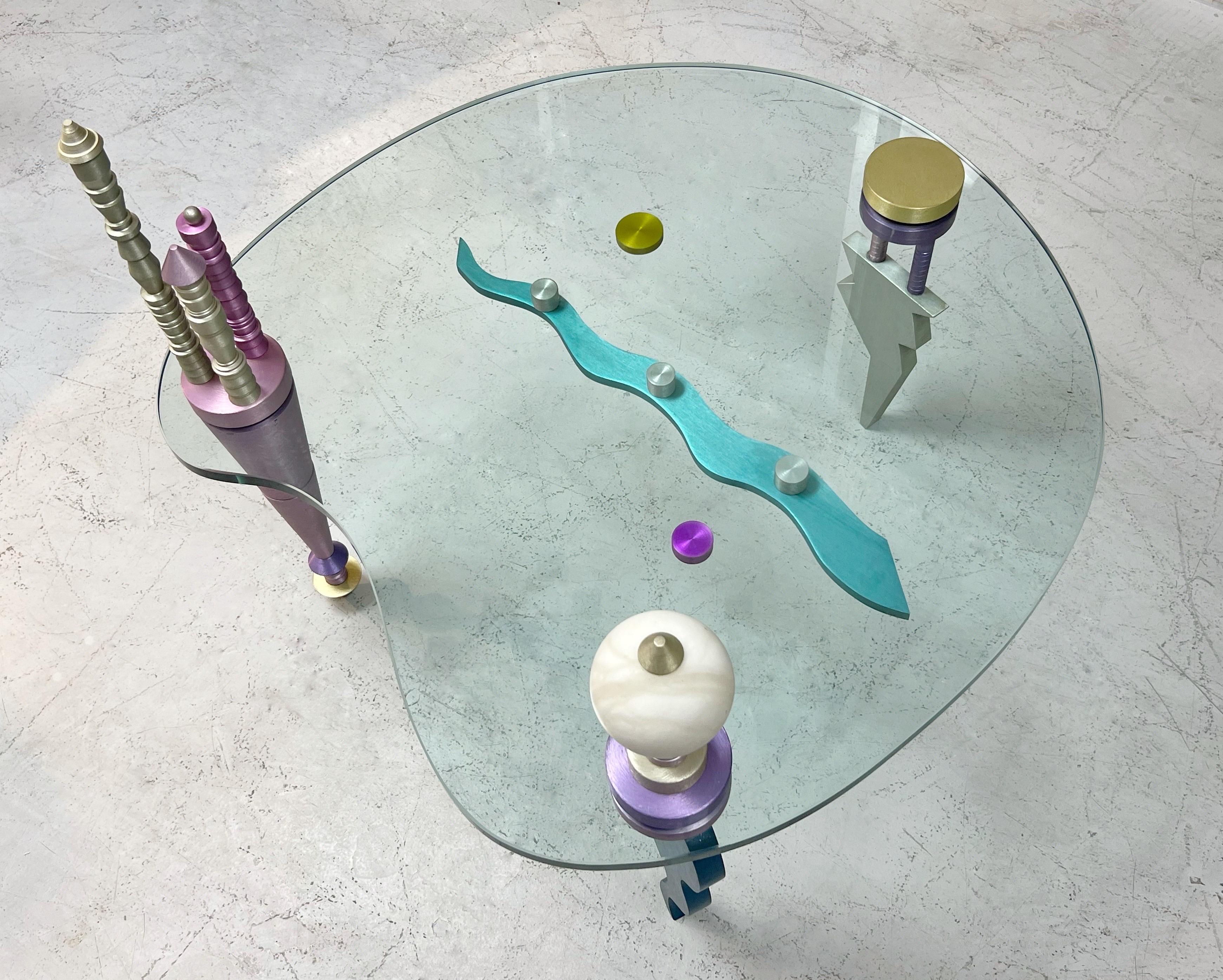 A unique coffee or occasional table. Free from glass with colorful anodized aluminum legs and finials. The metal elements are highly sculptural.