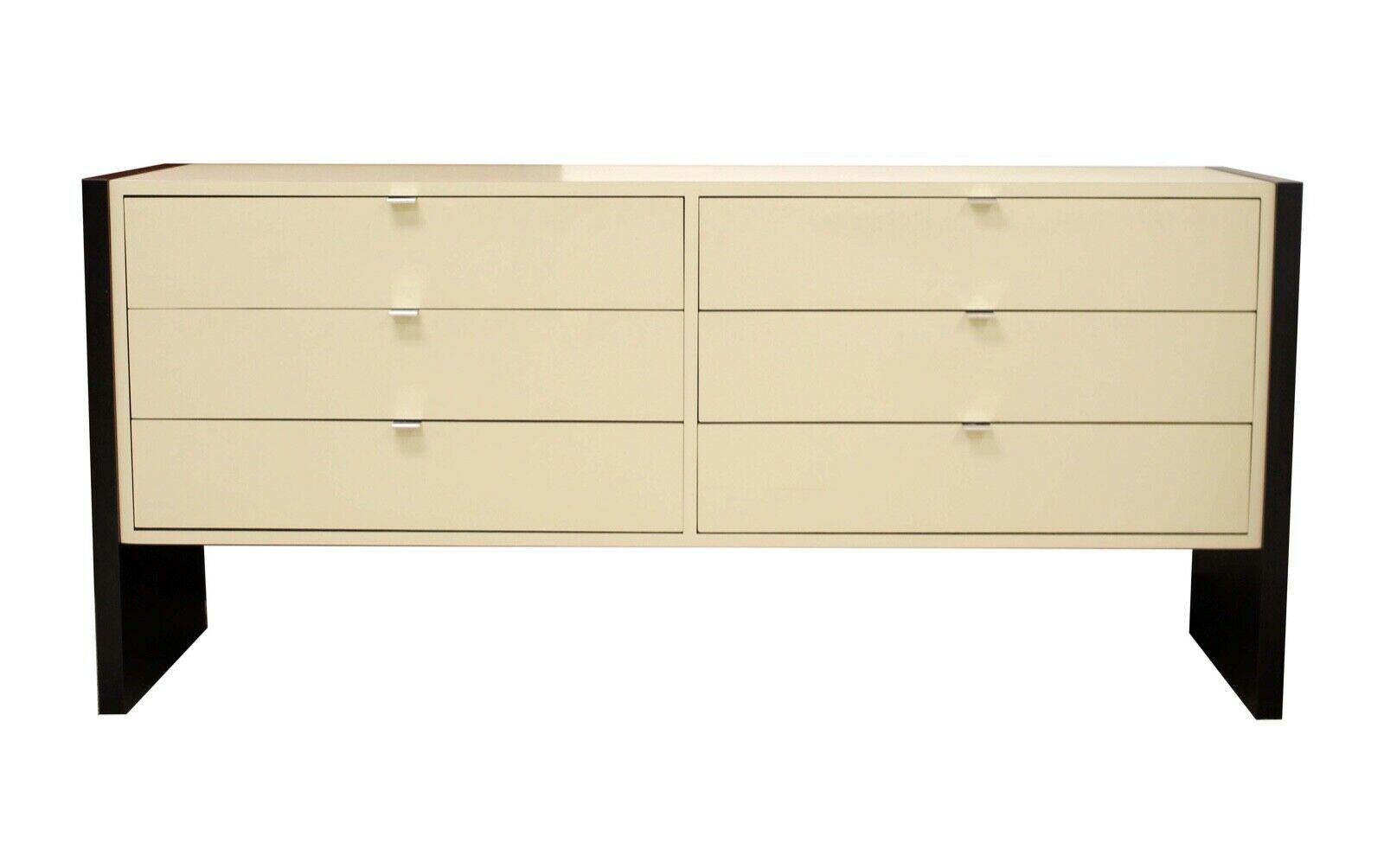 This Memphis Style dresser and pair of nightstands is detailed with white laminated drawers and black sides. The night stands each include two drawers with silver hardware while the matching dresser includes 6 large size drawers. Modern and