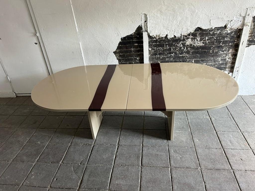 Mesa de comedor ovalada curvada Gema postmoderna de 10' de largo con (2) hojas. Tapa acrílica de alto brillo con un bonito color tostado topo con 2 rayas rojo oscuro granate. Base arqueada muy bonita con mecanismo de extensión suave. Mesa muy limpia
