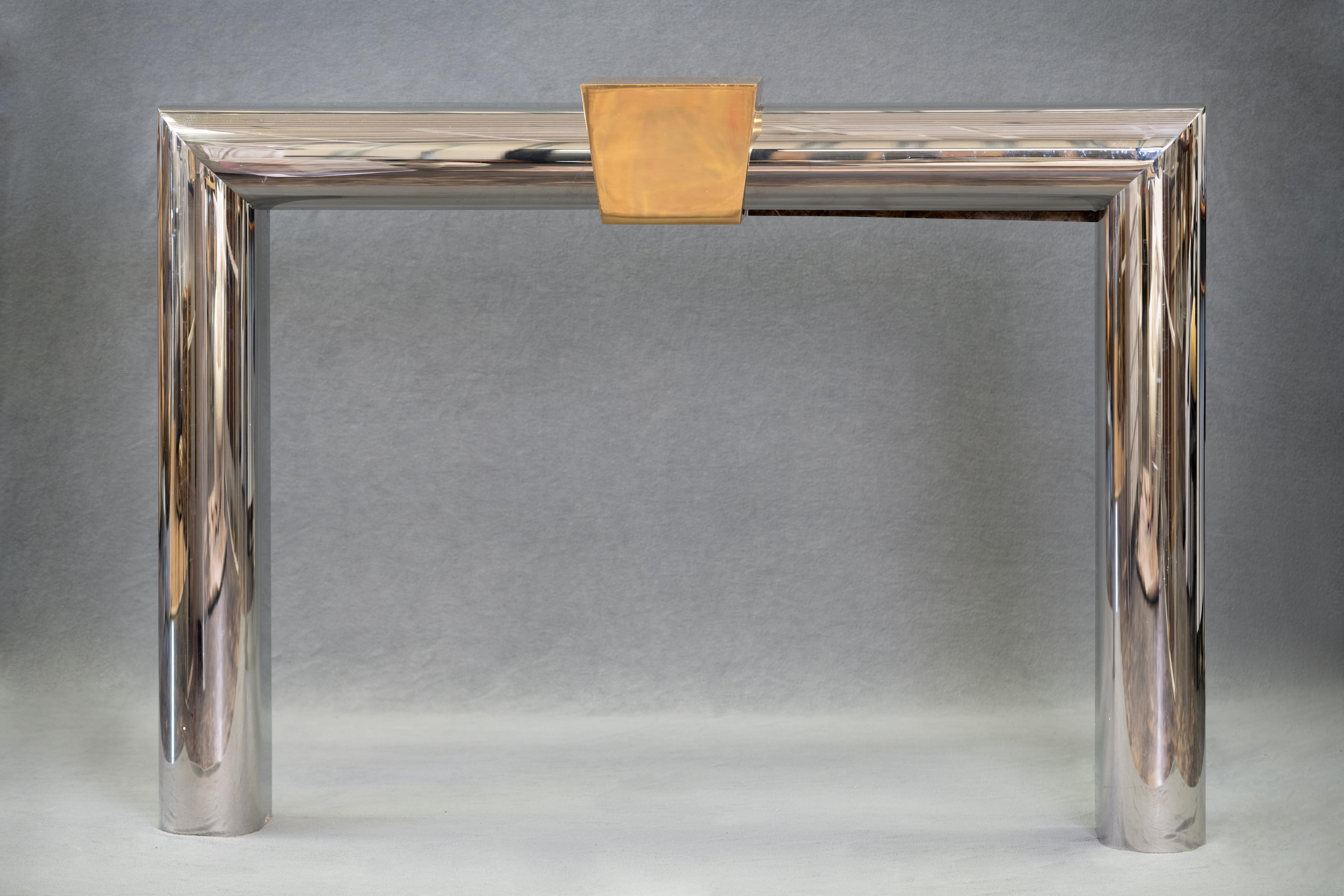 Fireplace surround in polished stainless steel with polished brass keystone by Danny Alesandro Ltd, American 1980's. This artisan fireplace surround is beautifully made and very unique - sometimes said to be reminiscent of Karl Springer- Danny