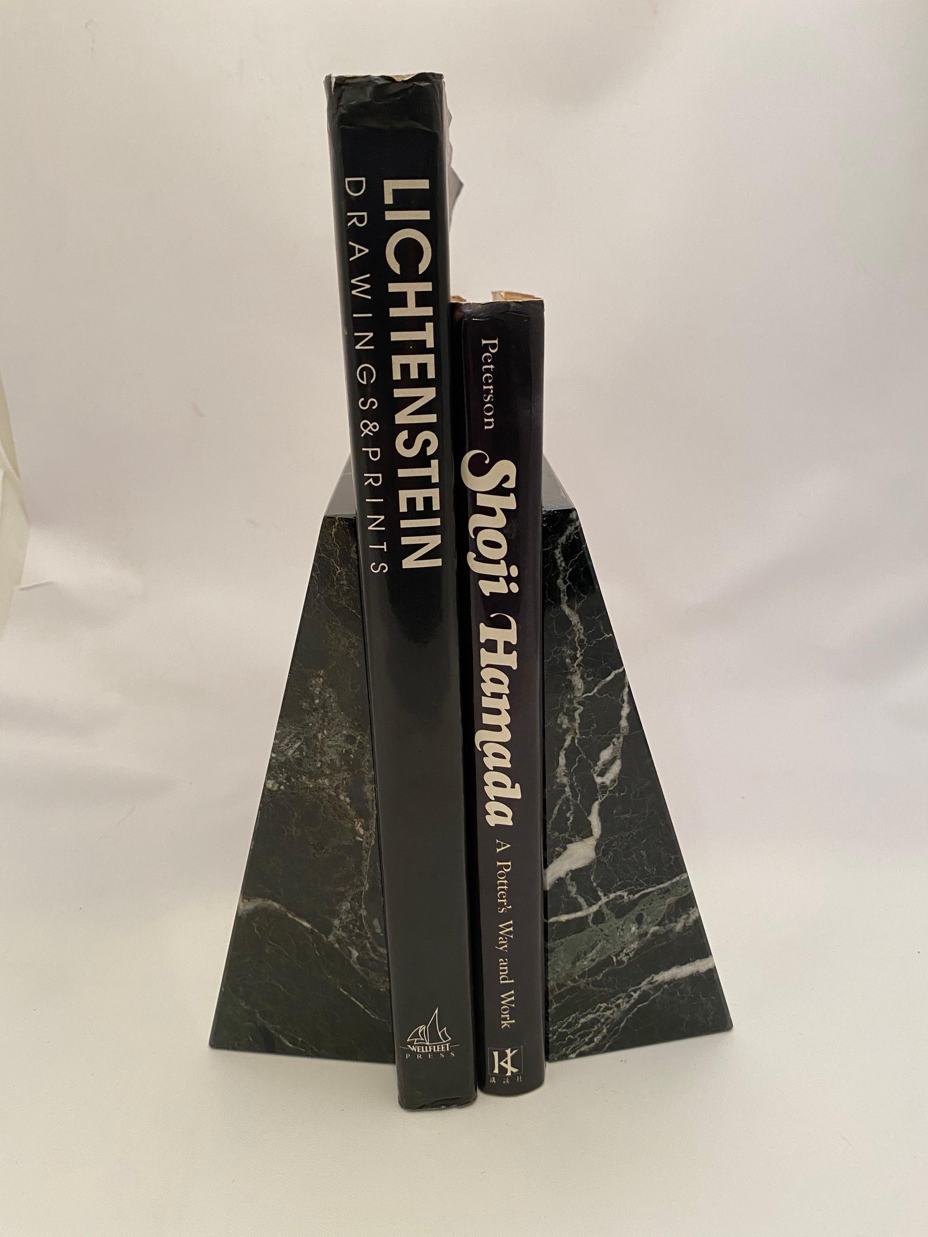 A pair of polished dark green (almost black) marble bookends. Austere wedge shape with gray and white veining. Circa 1980-90. Good condition with no major issues like chips or cracks. Minor scratches and wear commensurate with age and