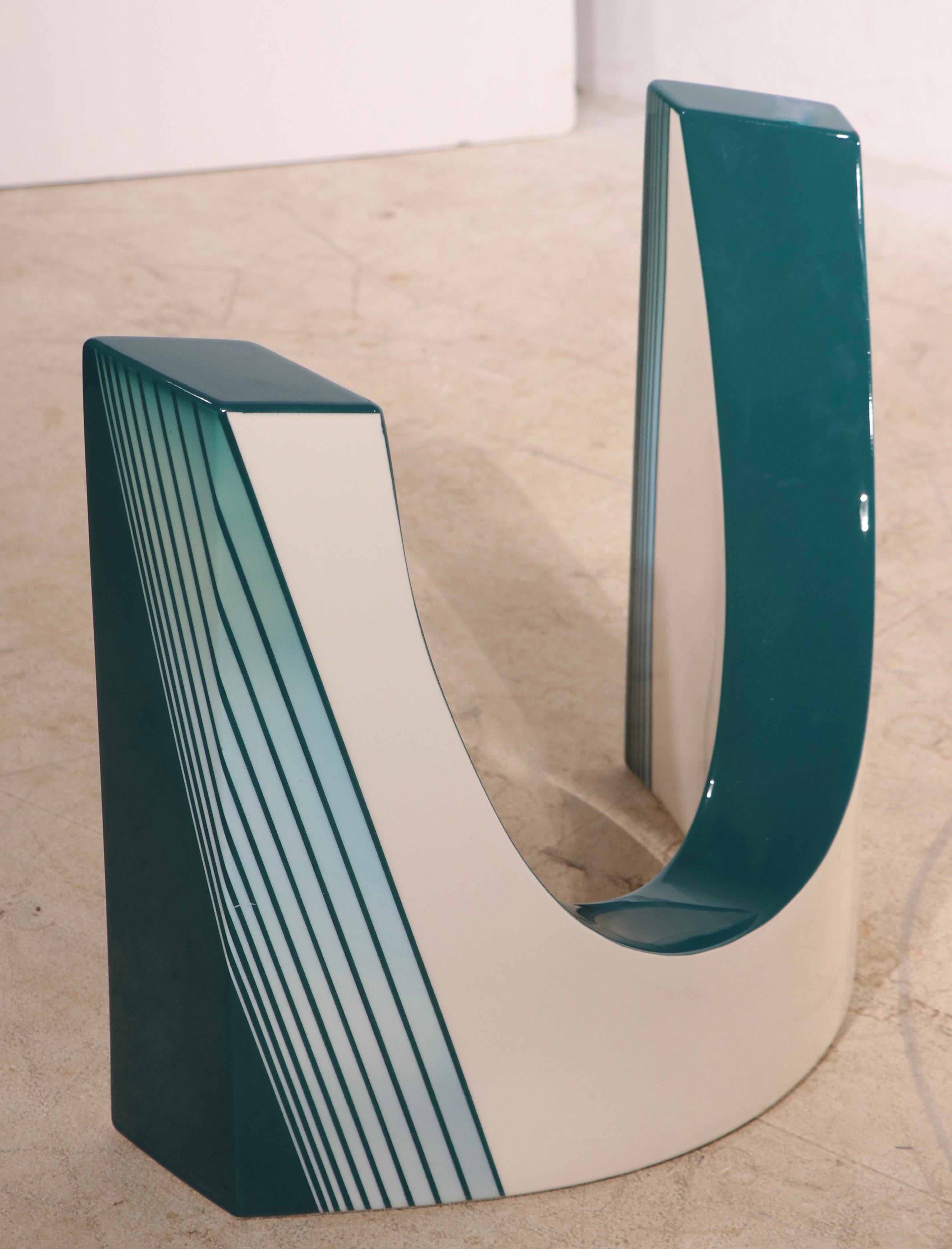 Intrigante table basse post-moderne de style Memphis, dont les bases courbes opposées, en métal émaillé turquoise et blanc, soutiennent l'épais plateau en verre biseauté (0,75 po). La table est en très bon état, originale, propre et prête à