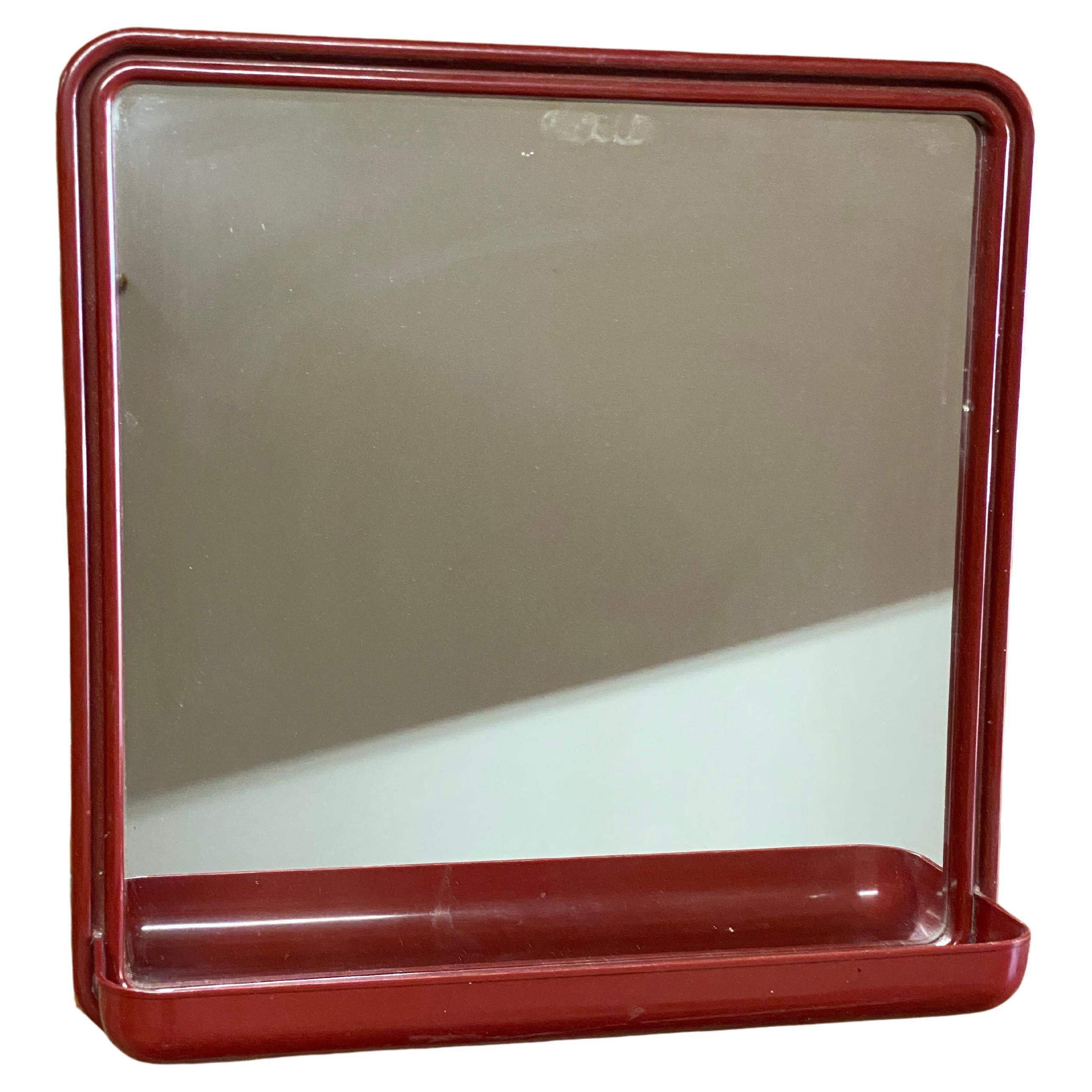 Finn mirror by Makisen Kuvastin OY, Vammala, Finland. Circa 1970-80. Maroon plastic wall mounted frame with a small extended tray. Fully signed on the reverse. Good overall condition with no visible cracks, chips, or restorations. There is one very