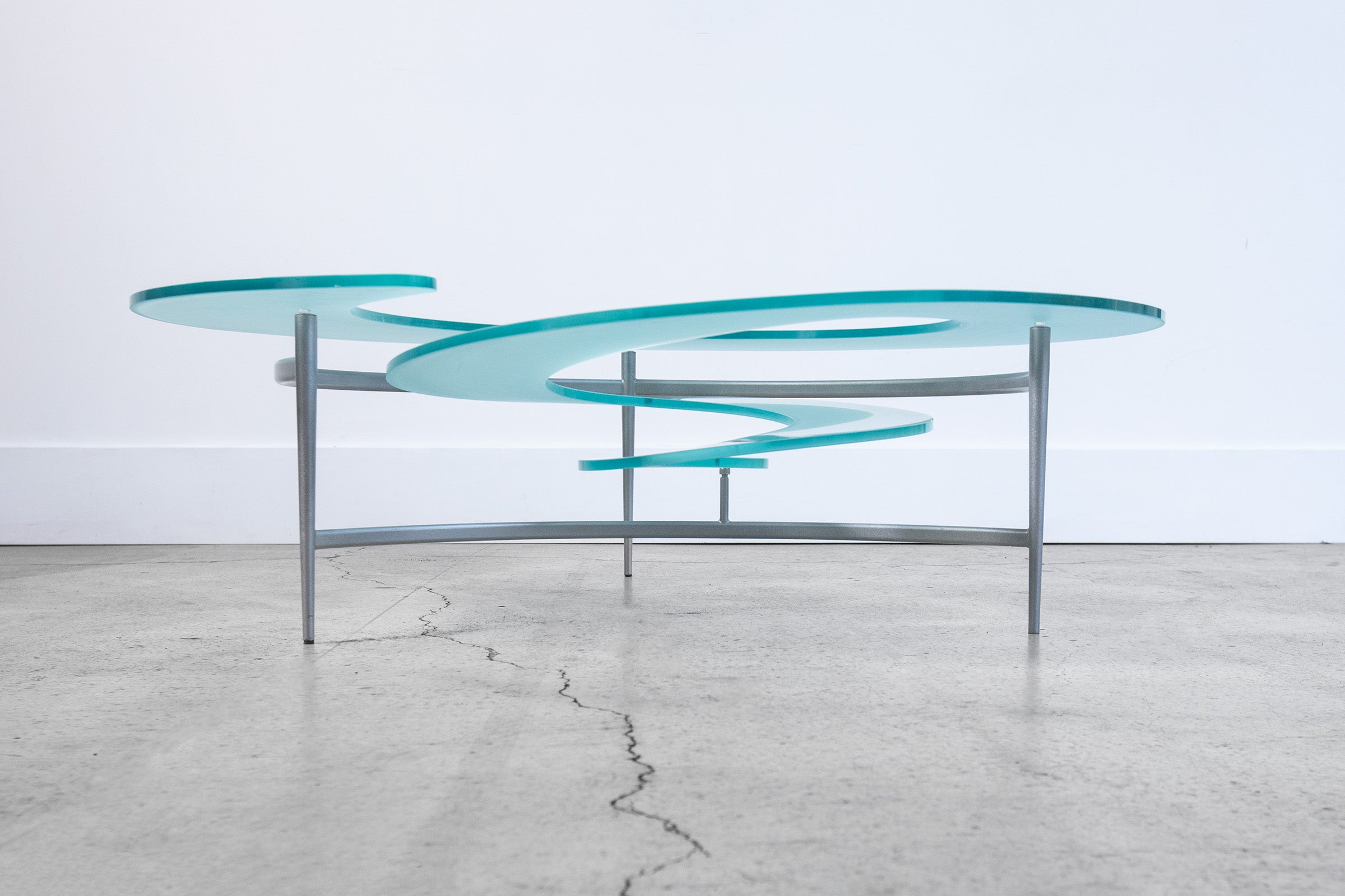 Post-modern sculptural nautilus spiral coffee or cocktail table rendered in sandblasted cut and bent glass with a titanium powder coated steel tripod frame, by Cattelan Italia, Italy, 1990s.