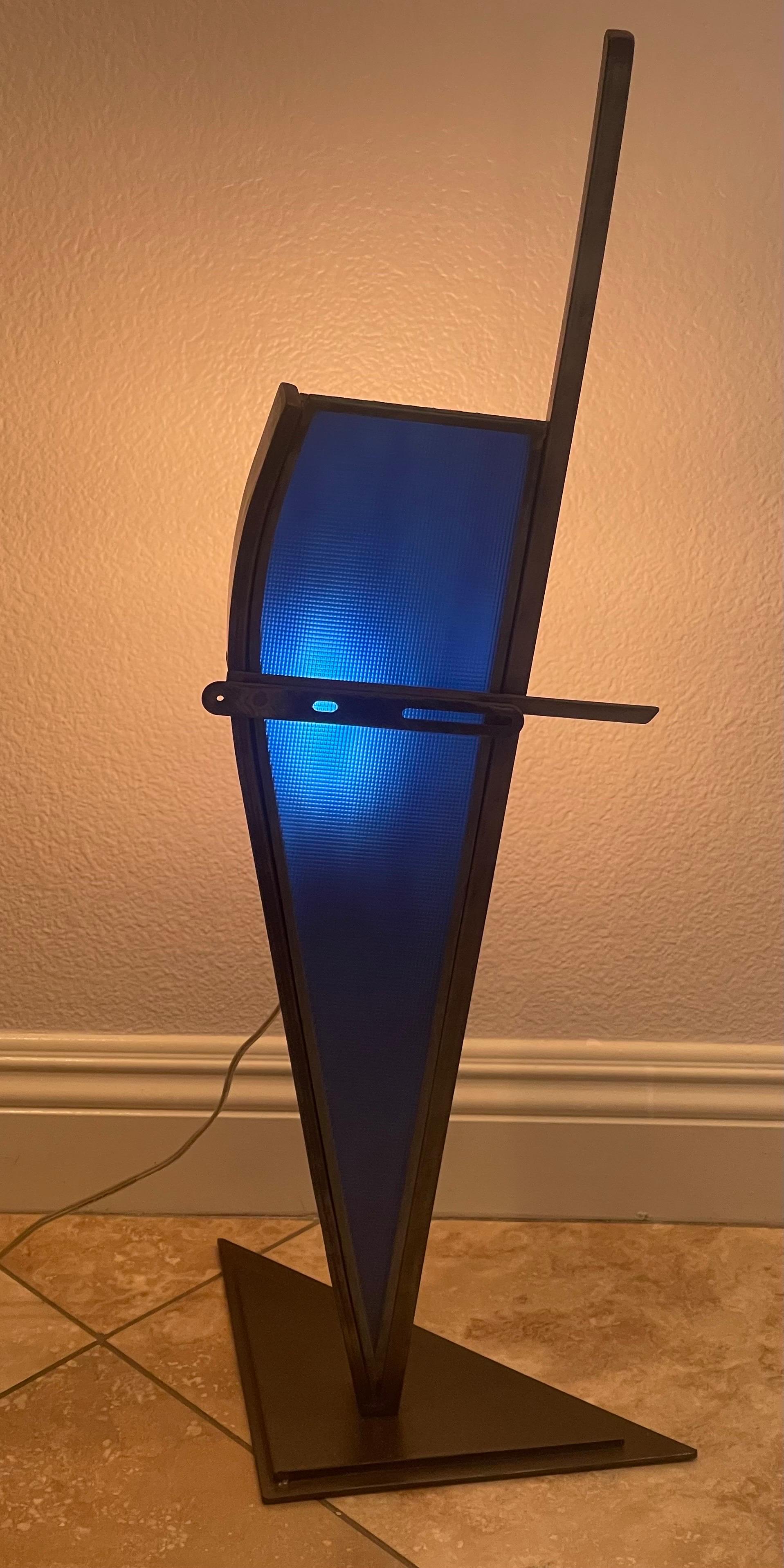A very cool post-modern glass and cut steel lamp by Karen Dugan, circa 2000s. The sculptural piece is made of dark cut steel with a blue glass frame the amplifies the light; it is in very good condition and measures 14
