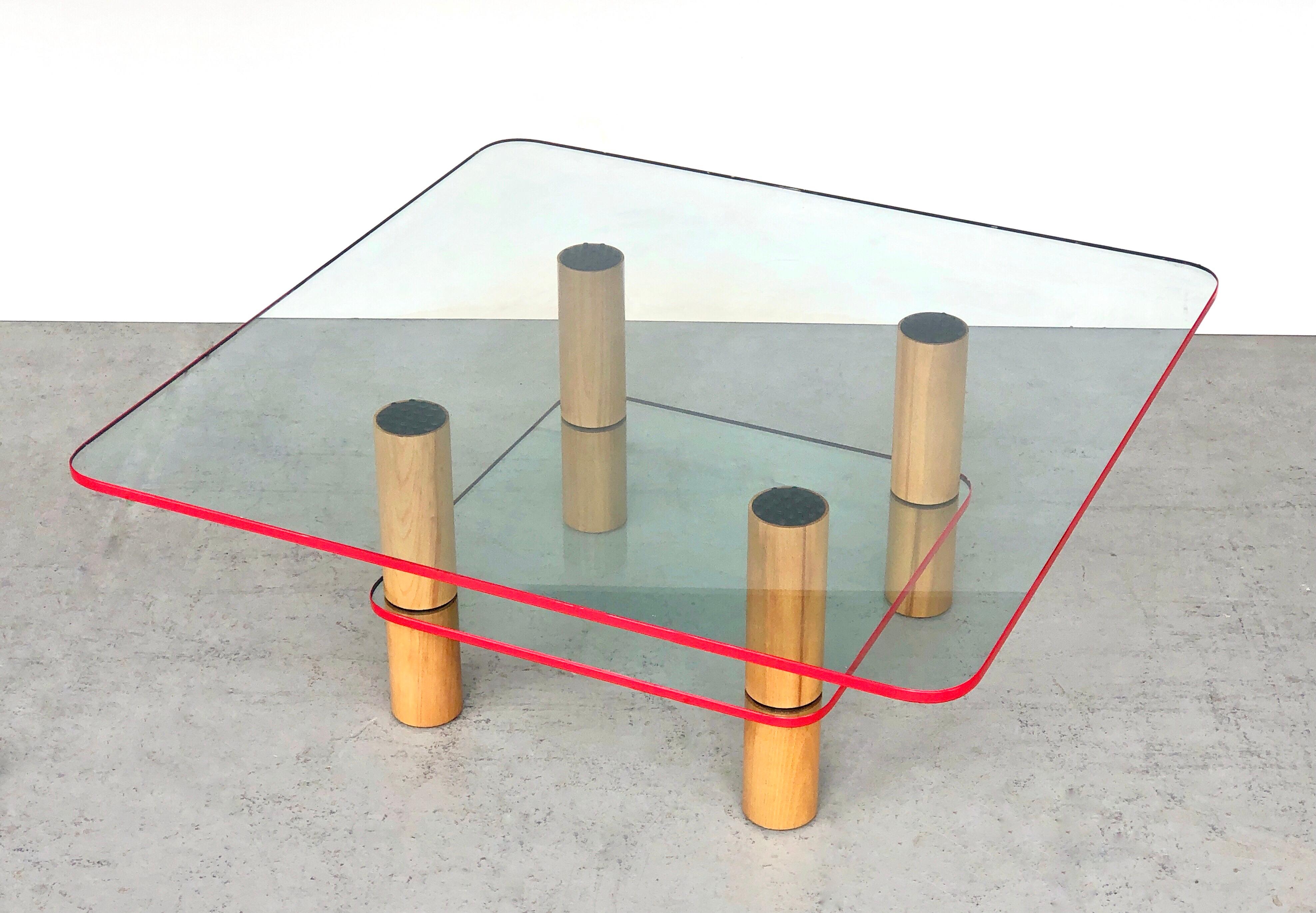 A very chic post modern coffee table. 2 glass levels on clean oak columns. The glass pieces have a red enamel edge. Striking post modern design but still visually light. 
Disassembles.