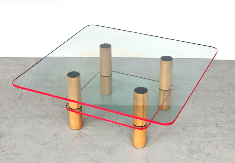 A very chic post modern coffee table. 2 glass levels on clean oak columns. The glass pieces have a red enamel edge. Striking post modern design but still visually light. 
Disassembles.