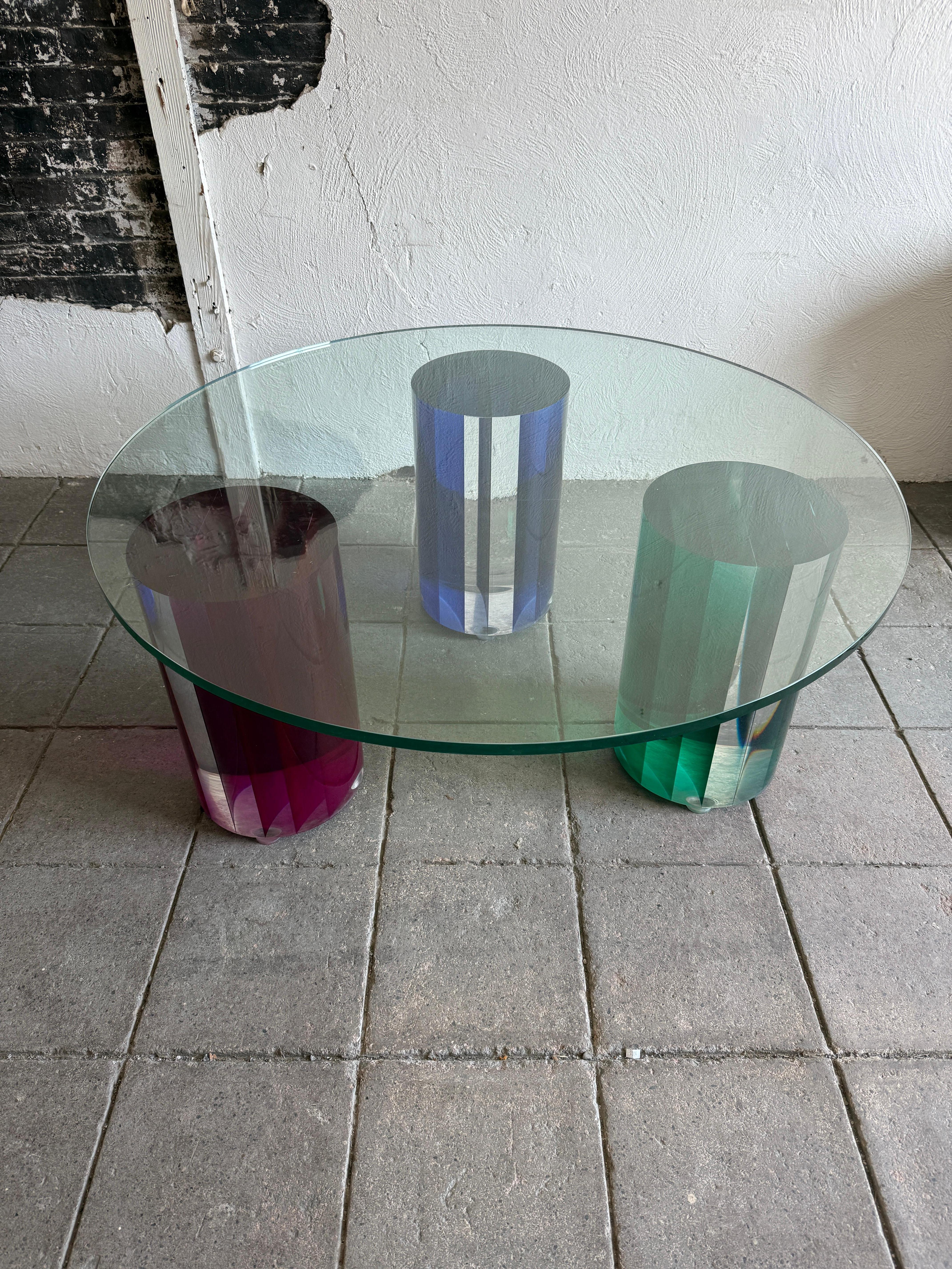 Unique Post modern glass Coffee Table with large color plexiglass round bases. Beautiful 3 base coffee table very colorful large solid joined plexiglass round bases. (1) blue (1) green and (1) purple. The glass top is 48” in diameter and 3/4” thick.