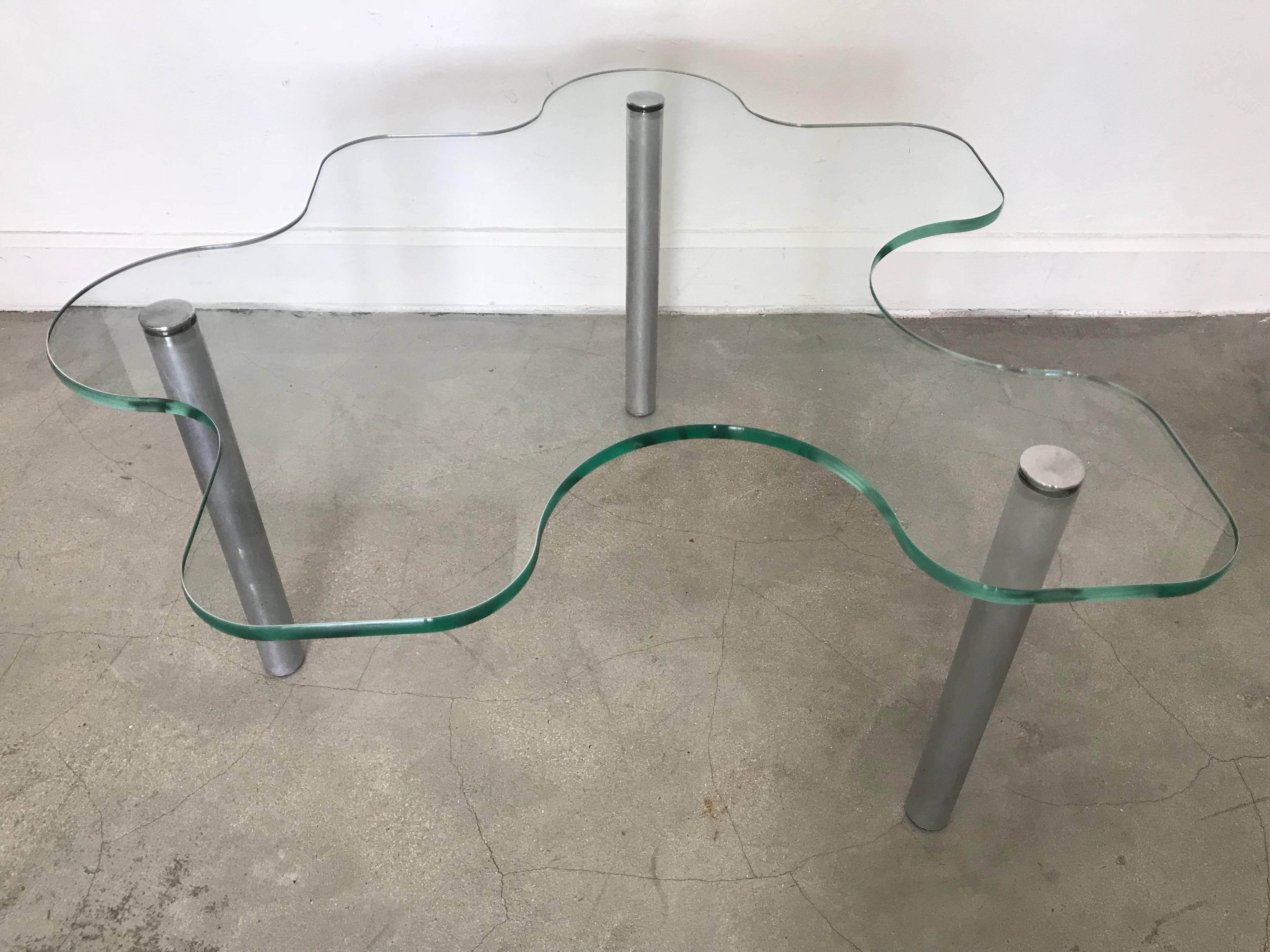 Glass and steel table in the shape of a jigsaw puzzle game piece. Great size and scale to be used as a coffee, cocktail, side, or end table.