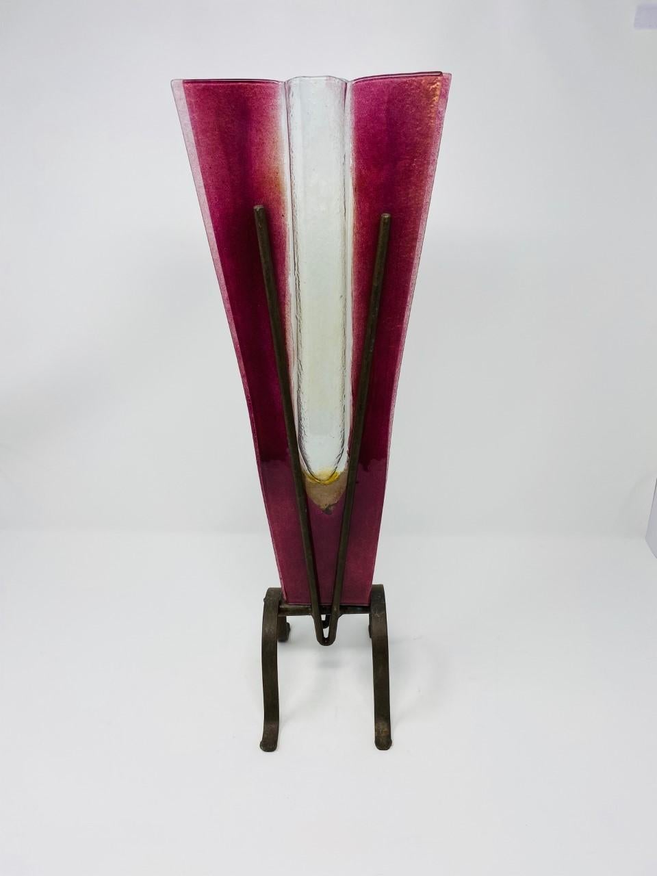 Impactful piece of glass that brings lines and design to your décor. This postmodern piece consists of two pieces: Blown glass in a purple hue is conjoined and shaped into a V shaped vessel. A metal base holds the glass vessel in place adding height