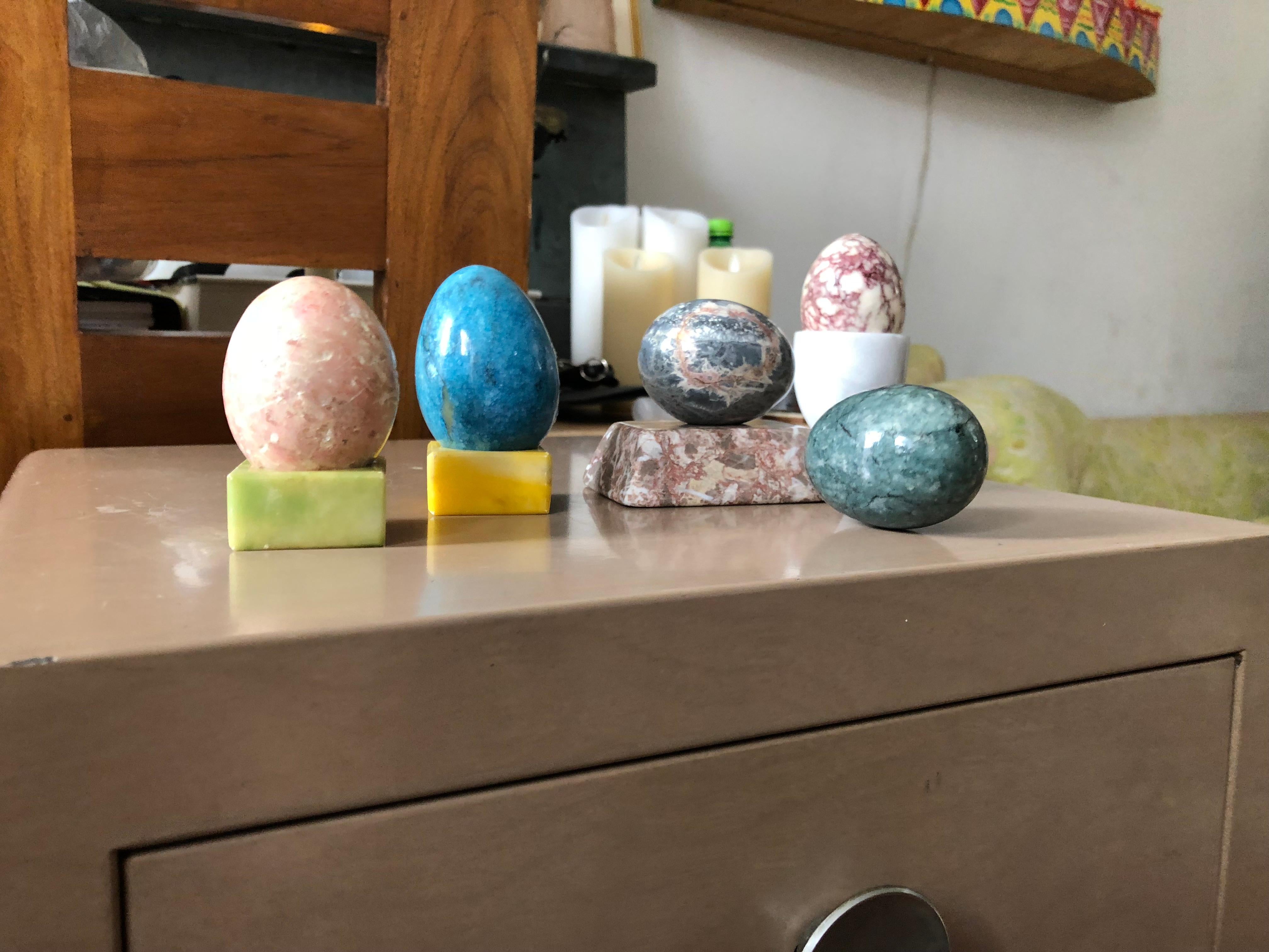 Carefully curated set of semi-precious stone eggs in vibrant pastels with corresponding stone platform bases for display. Set is comprised of 5 eggs and 3 stone bases and one white egg holster. 