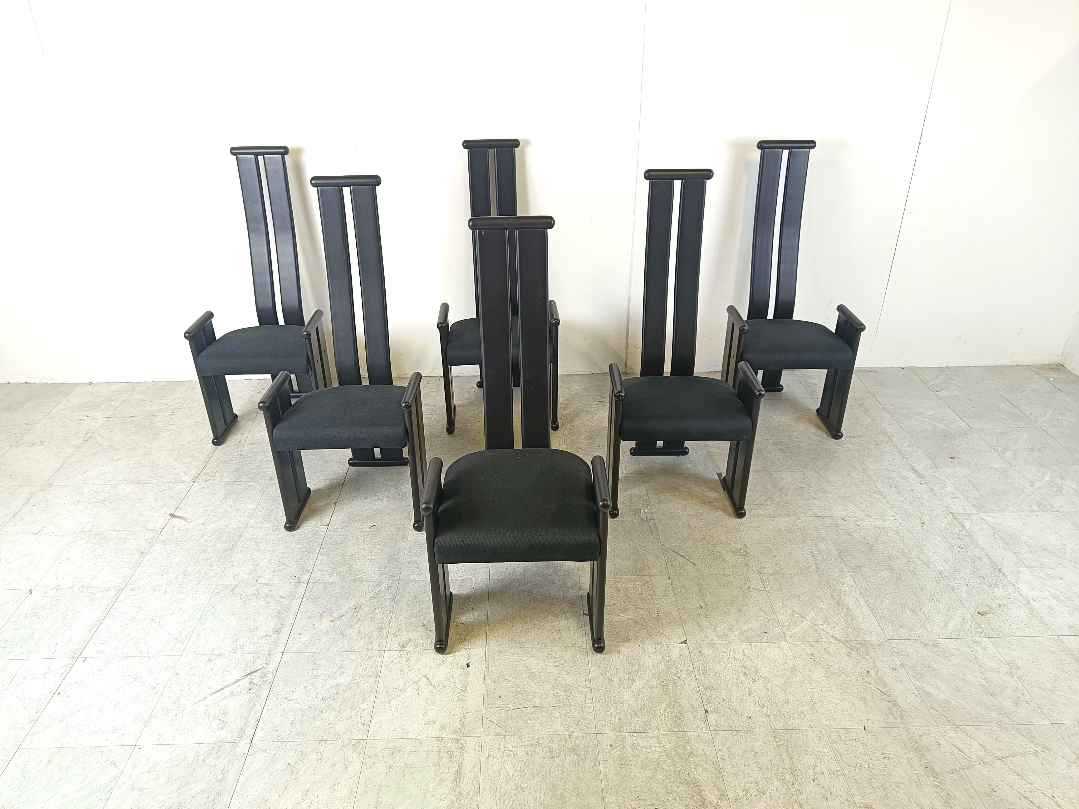 Striking vintage dining chairs with black ebonized wooden frames and a black fabric seat.

The post modern design with the long curved backrests is strongly inspired by the Golem chairs by Vico Magistretti.

Very cool chairs by an unknown designer.
