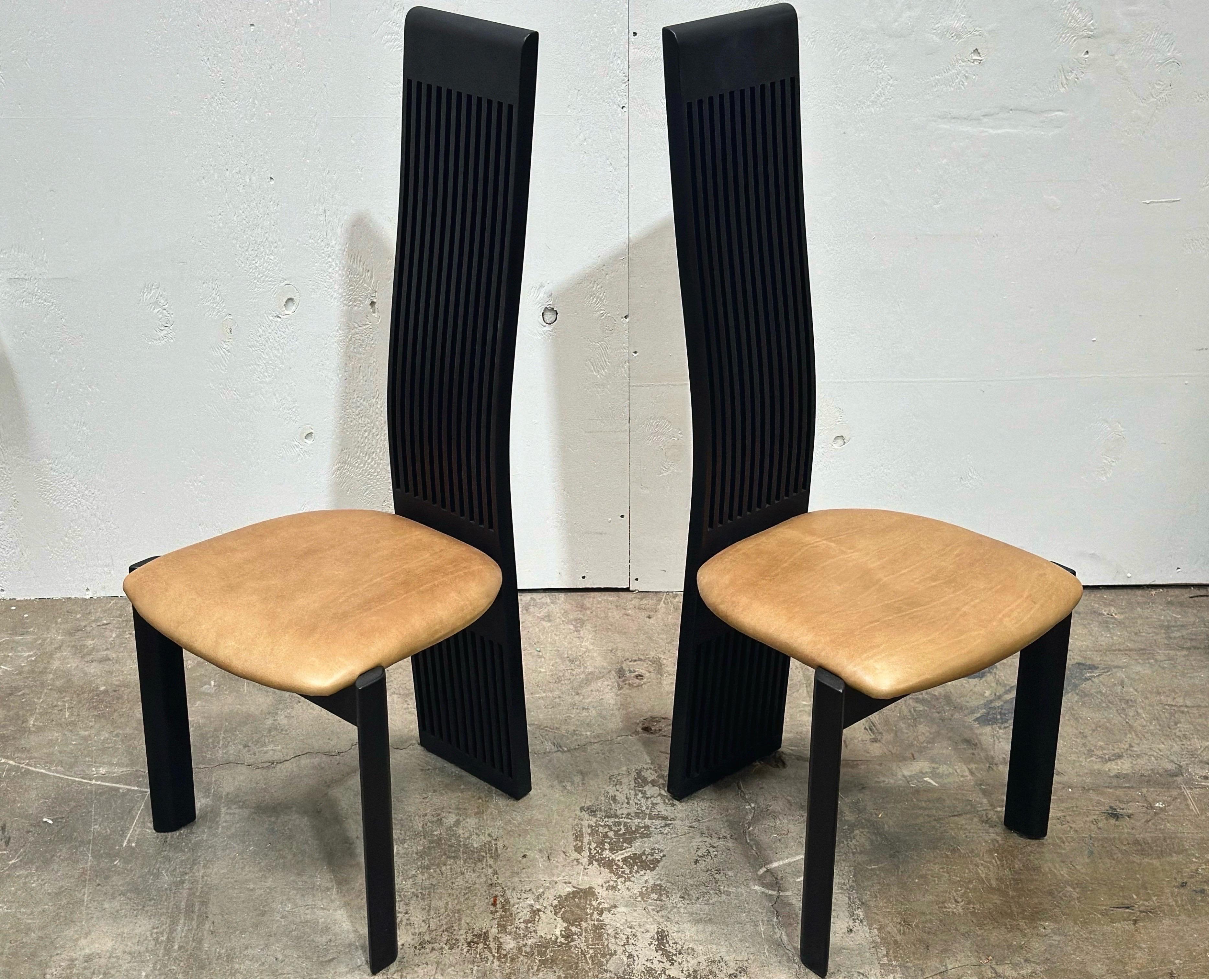 Une paire / un ensemble de deux chaises de salle à manger post-moderne à haut dossier de Pietro Costantini avec des dossiers à lattes exagérées et des sièges en cuir.

Construit en bois de hêtre massif avec une finition laquée noire semi-brillante,