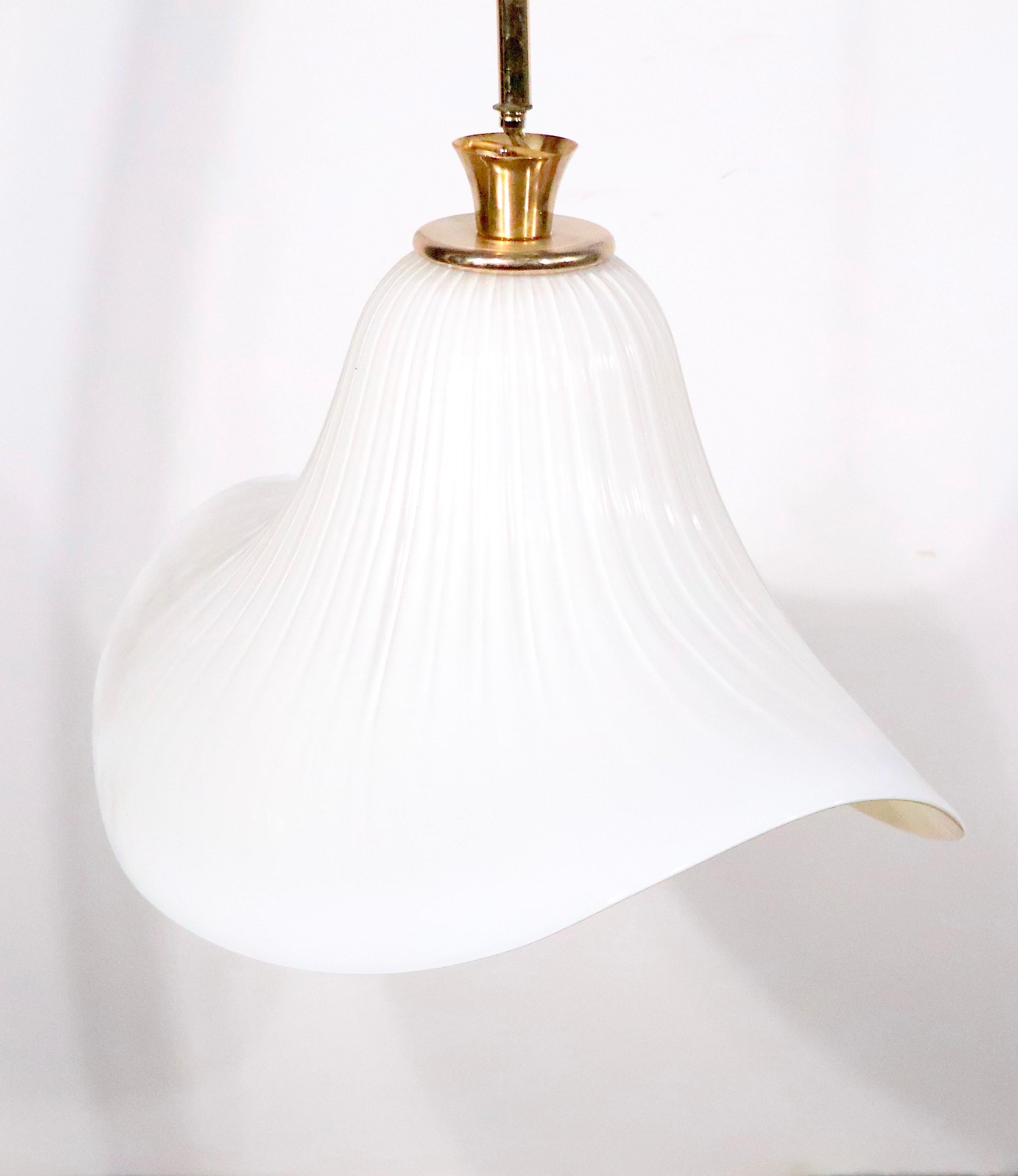 Glamorous high style Murano glass chandelier, circa 1970/1980's. The bell, or hat, shaped glass shade is supported by its original brass vertical post. The shade is in off white color, with a ribbed textured exterior.  The fixture is in working, 