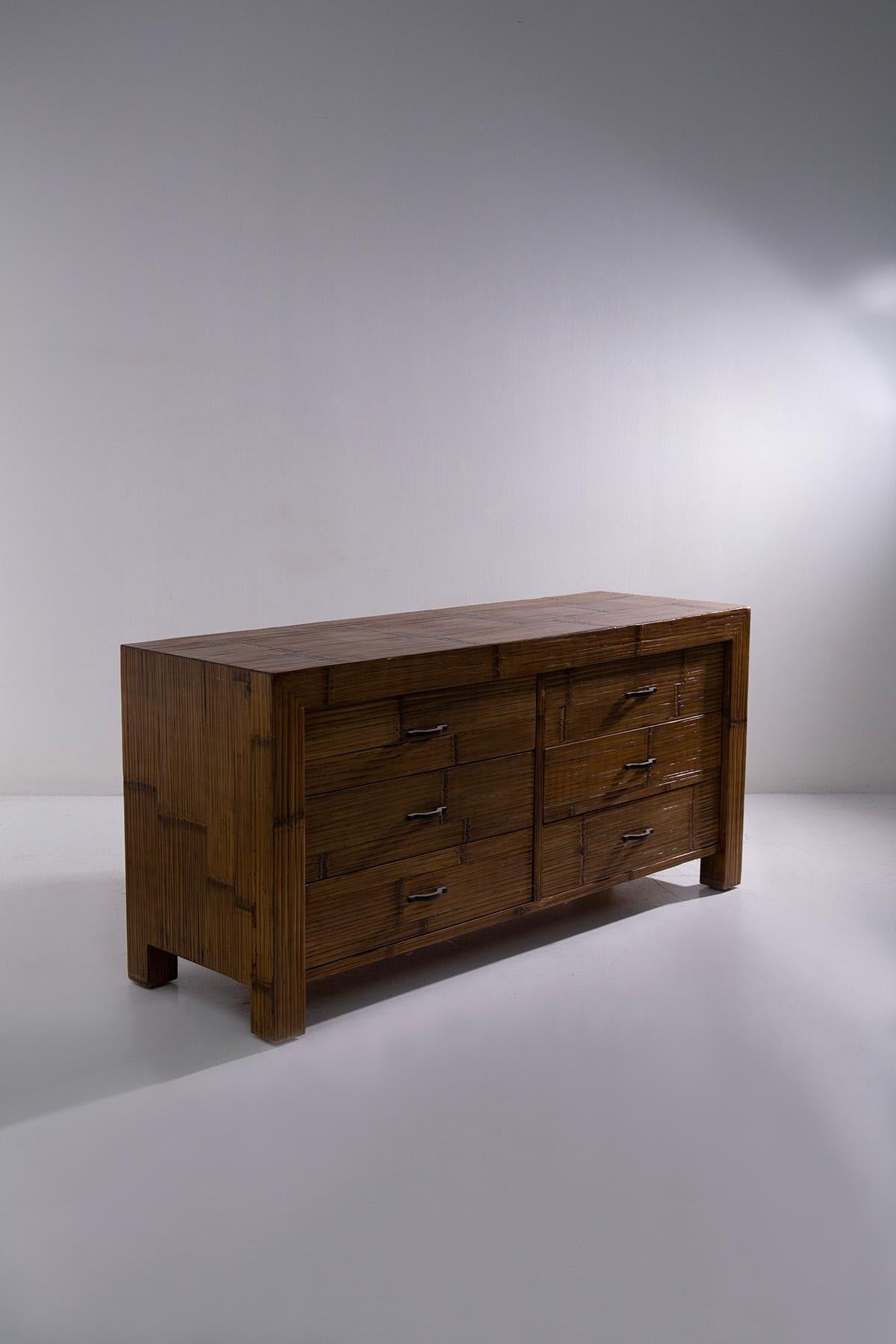 The eccentric Italian post-modern sideboard from the late 1980s to early 1990s is a striking blend of bold design and natural elements. Upholstered entirely in bamboo canes, it exudes a unique charm that effortlessly combines natural chic with a