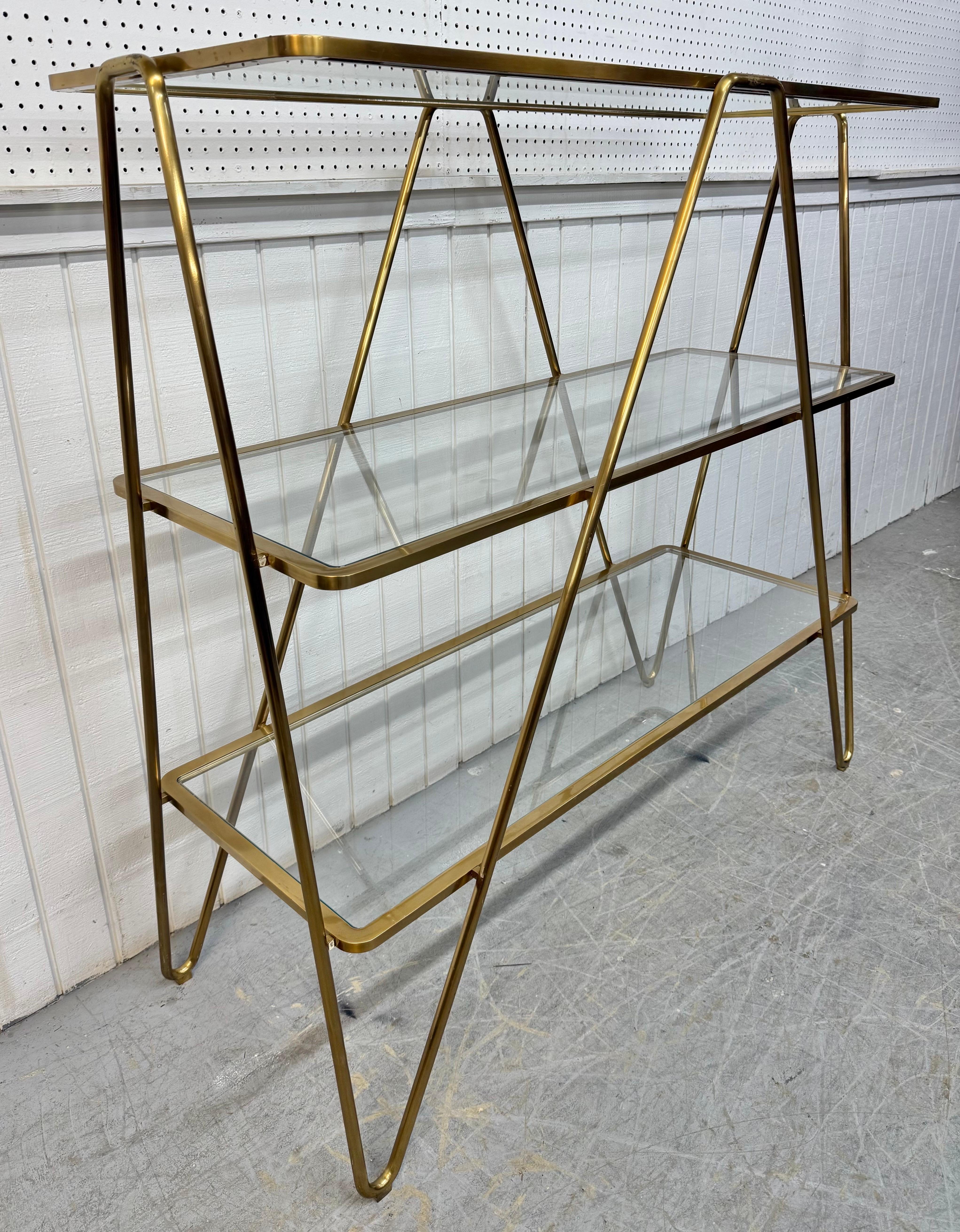 Cette annonce concerne une étagère en épingle à cheveux post-moderne italienne en laiton et verre. Avec un design en épingle à cheveux à trois niveaux, des étagères rectangulaires en verre et une finition en laiton doré. Il s'agit d'une combinaison