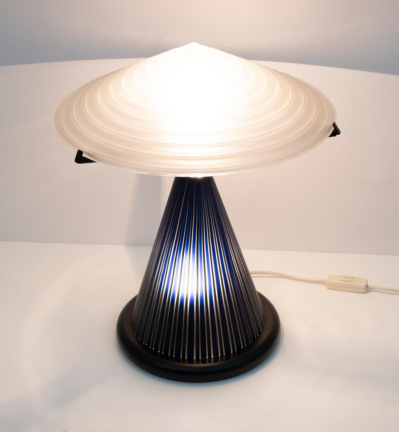 Table lamp produced in Murano by the Masters of Murano, conical base in blown glass with colored rods, hat in white etched glass. The lamp has a double switch, as in the photo it is possible to illuminate the lower part, with a softer light, or