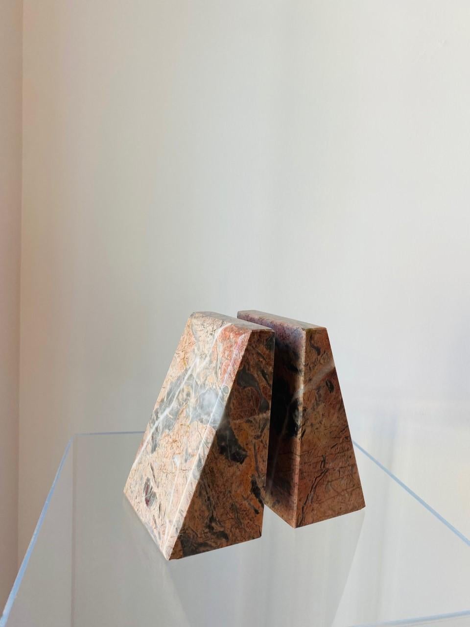 Beautiful pair of postmodern marble bookends from Italy. These sizeable pieces of marble are captivating as they are commanding. The veining that develops on the pink marble with pink and beige undertones ondulates as the shape forms columns that