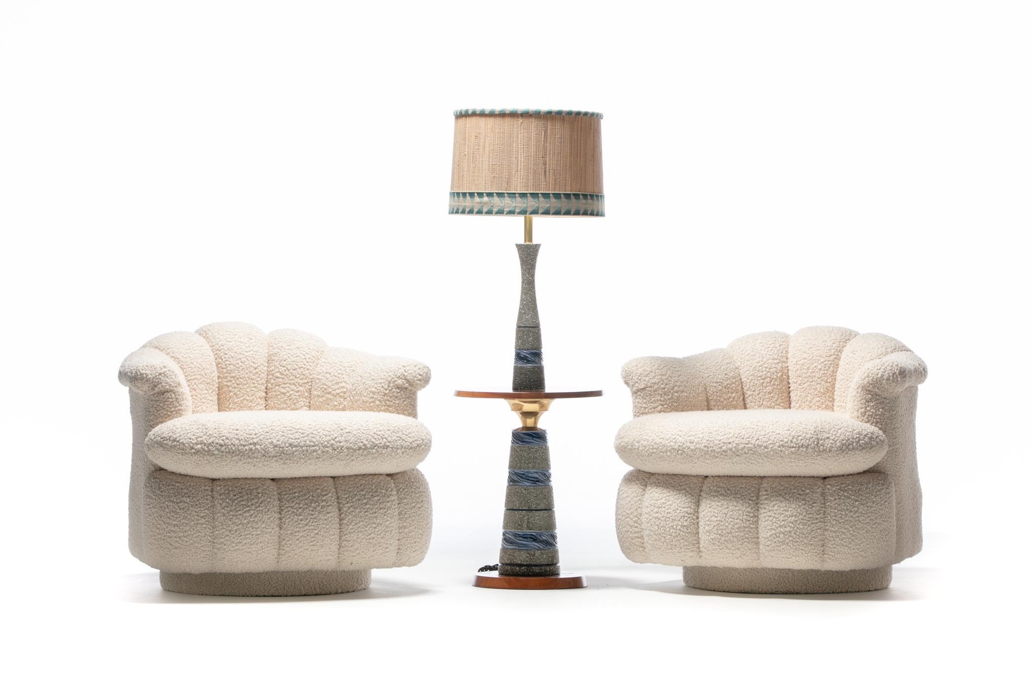 Luxurious pair of channeled Post Modern swivel chairs freshly reupholstered in soft ivory white bouclé. Shawl collar seat backs are channeled and curvy and convey a confident elegance. They roll out into scroll ends - the illusion of a fountain back