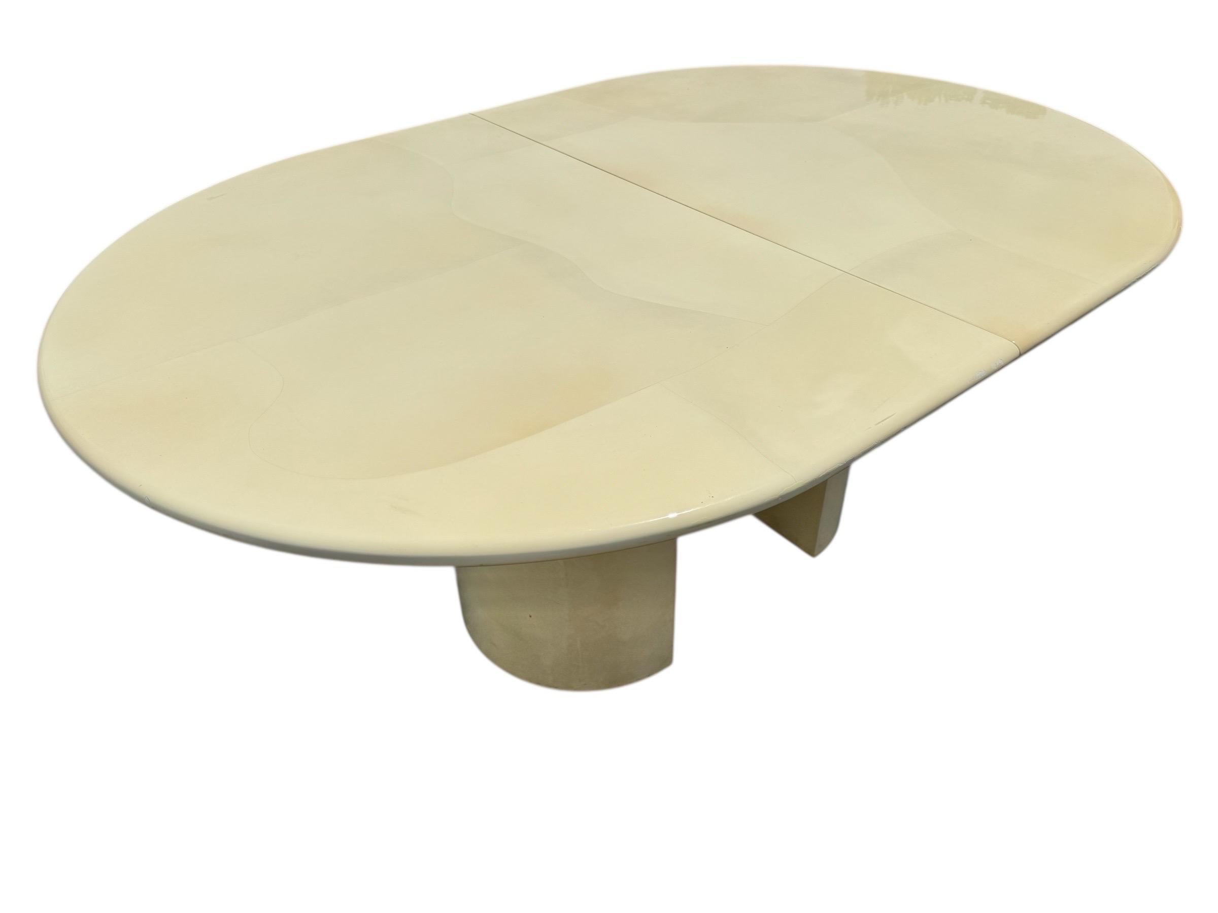 This listing is for a Post Modern Karl Springer Style Lacquered Dining Table. Featuring a Karl Springer style design, oval top with two leaves to extend the table up to 108” L, two demilune pedestal bases, and an original cream lacquer finish. This