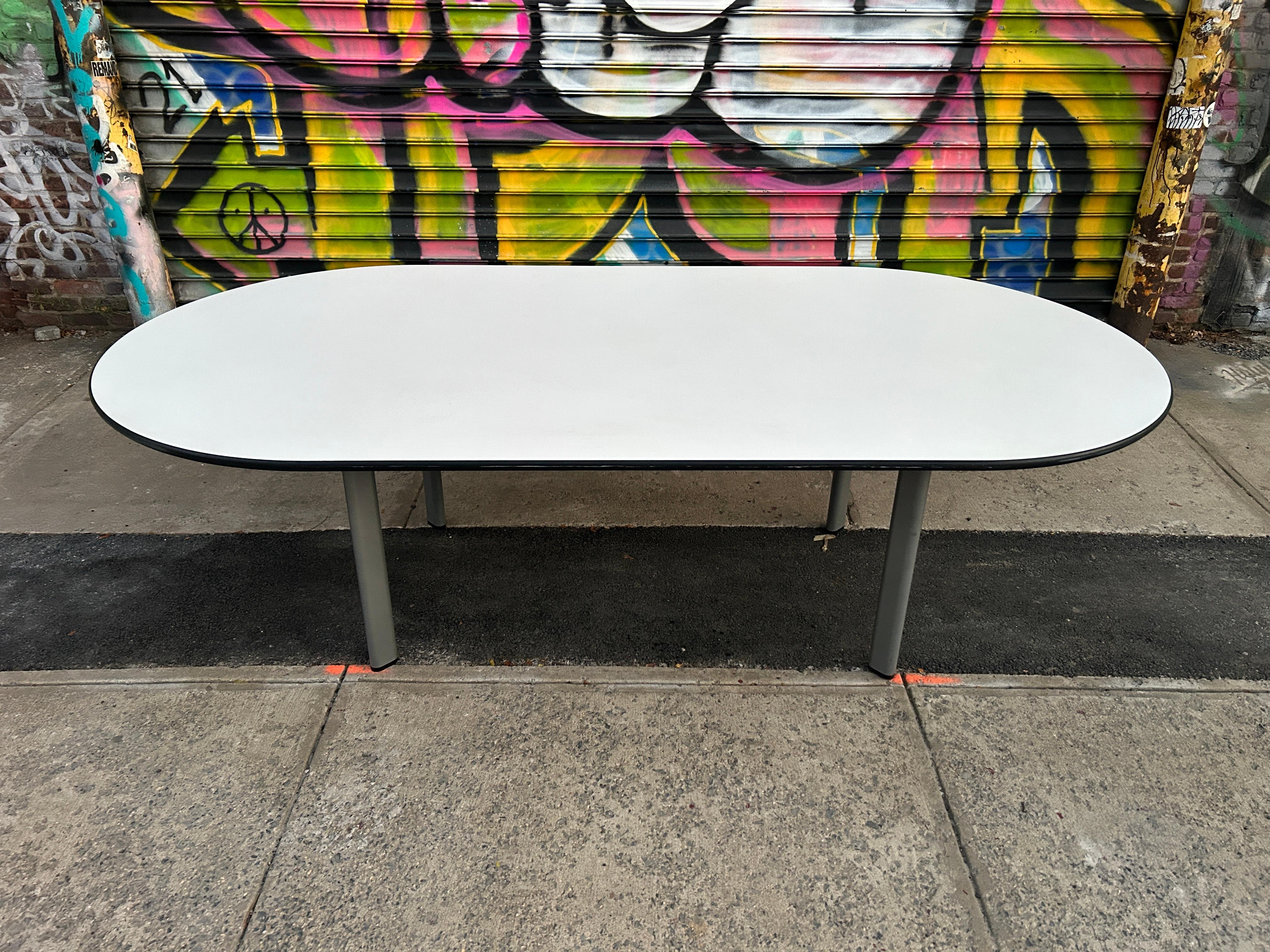 Post modern Knoll white laminate racetrack dining table by joe d'urso. Simple design oval conference or dining table with white laminate top and rubber edge molding that sits on 4 steel oval tube legs with frame. Legs unbolt and base unscrews. Good