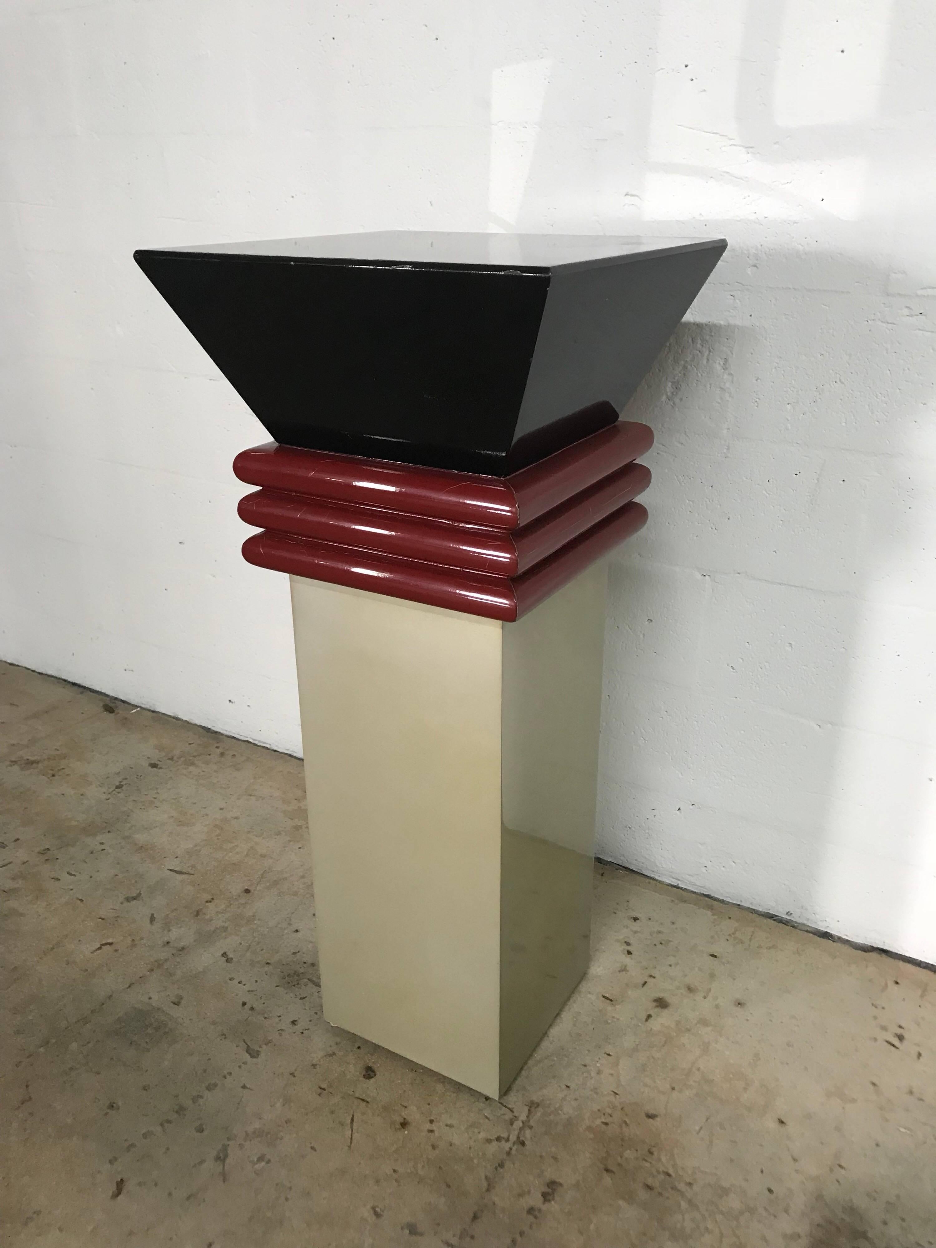 Postmodern Memphis style lacquered pedestal in 3 colors, black, burgandy, and a metallic gold.  This pedestal is great for displaying objet d'art and is an art piece in itself, USA, circa 1980s.